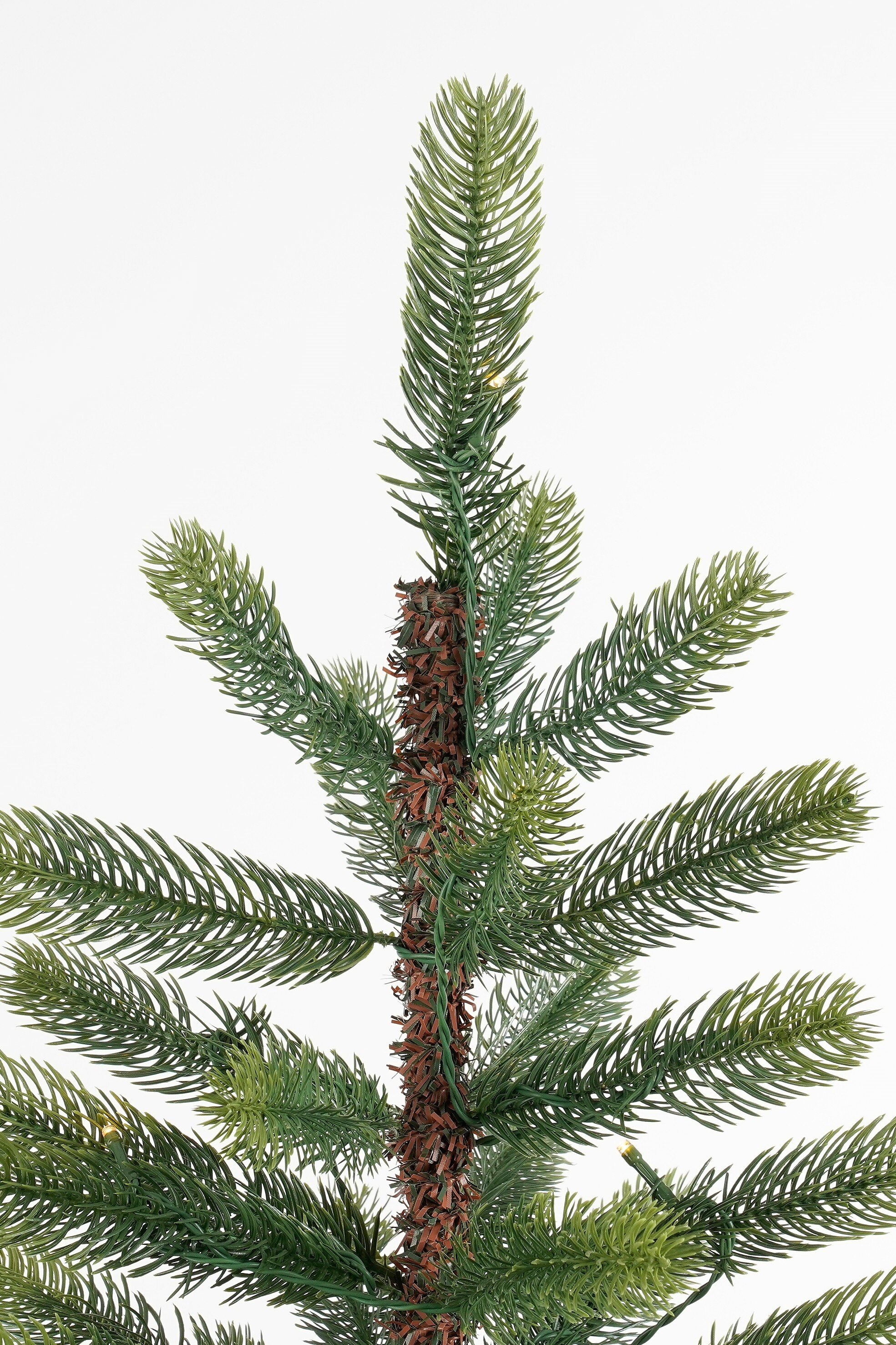 Un sapin de Noël artificiel vert avec un tronc marron sur fond blanc.