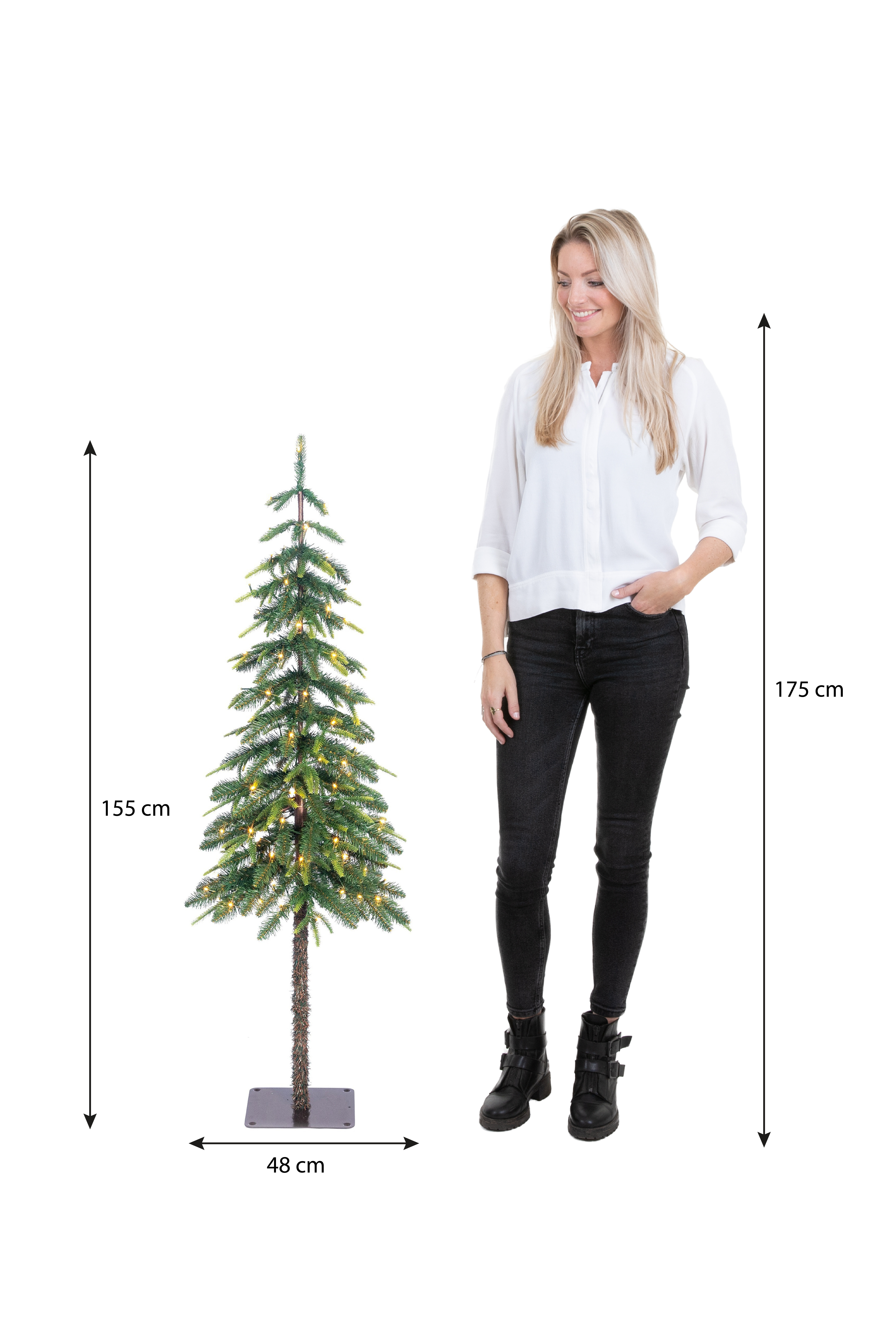 Une femme se tient près d'un sapin de Noël. L'arbre est éclairé. Des mesures sont indiquées.