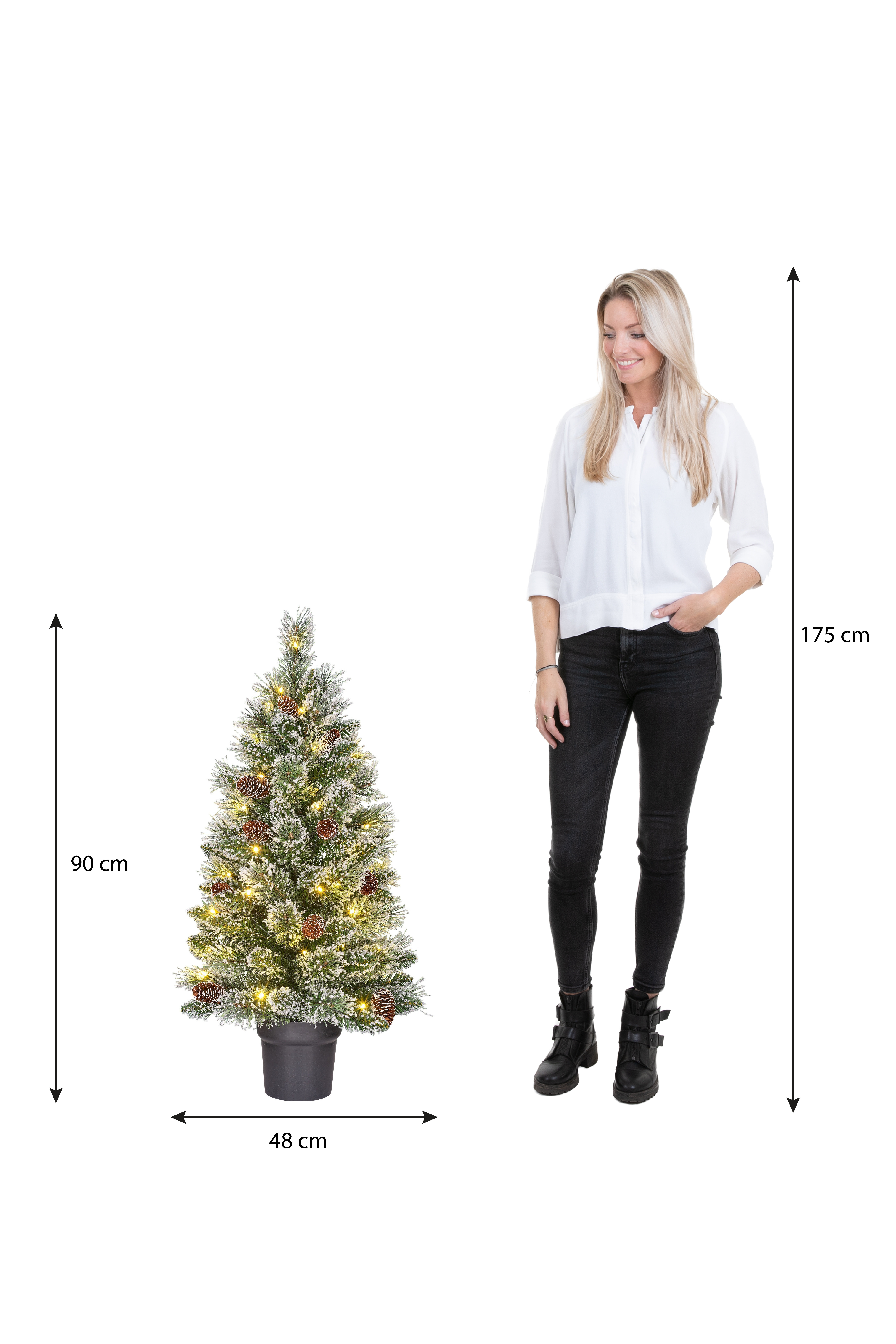 Une femme se tient près d'un sapin de Noël décoré. Les dimensions sont indiquées pour les deux. Fond blanc.