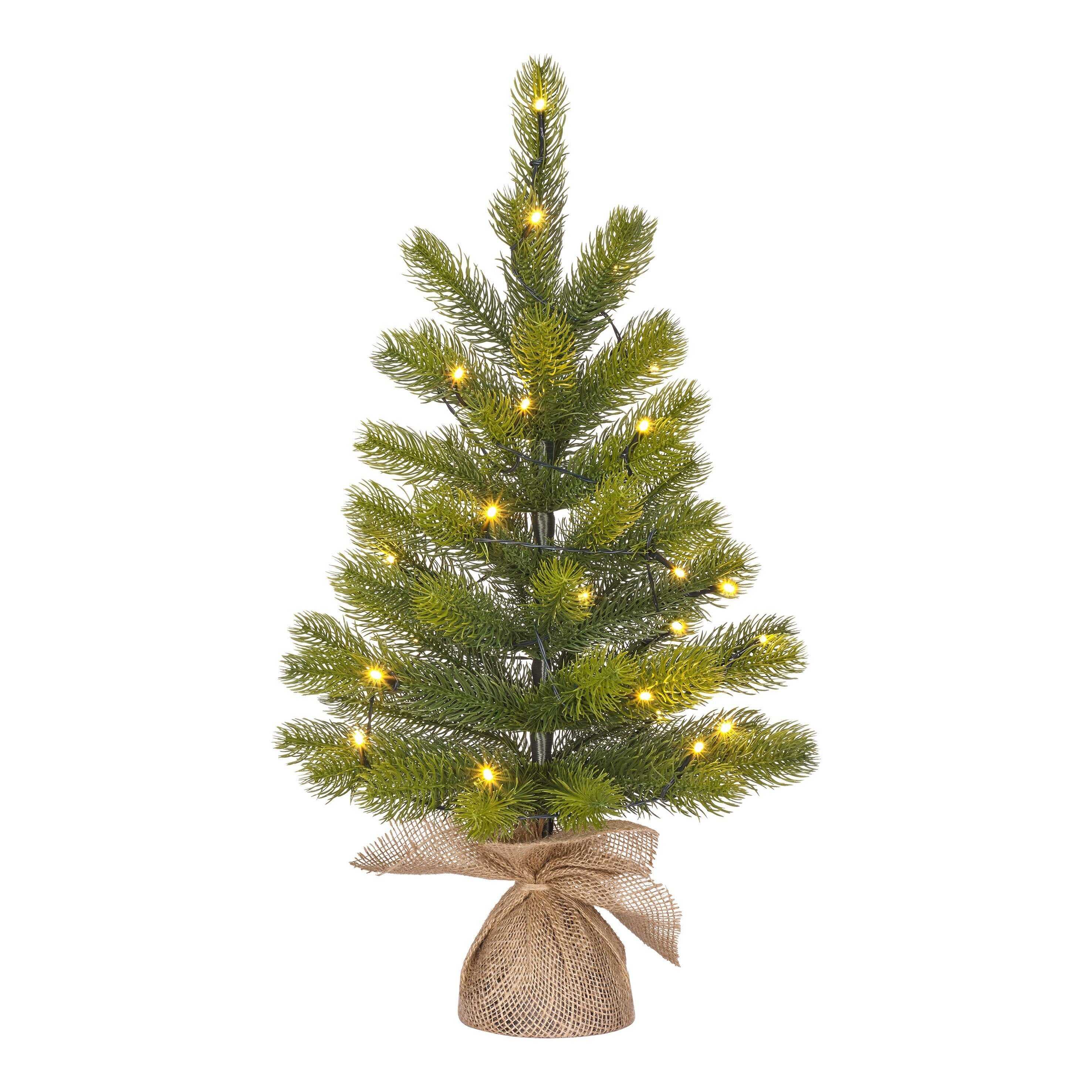 Un petit sapin de Noël avec des lumières. Il a des aiguilles vertes et est dans un sac en toile de jute. Le fond est blanc.