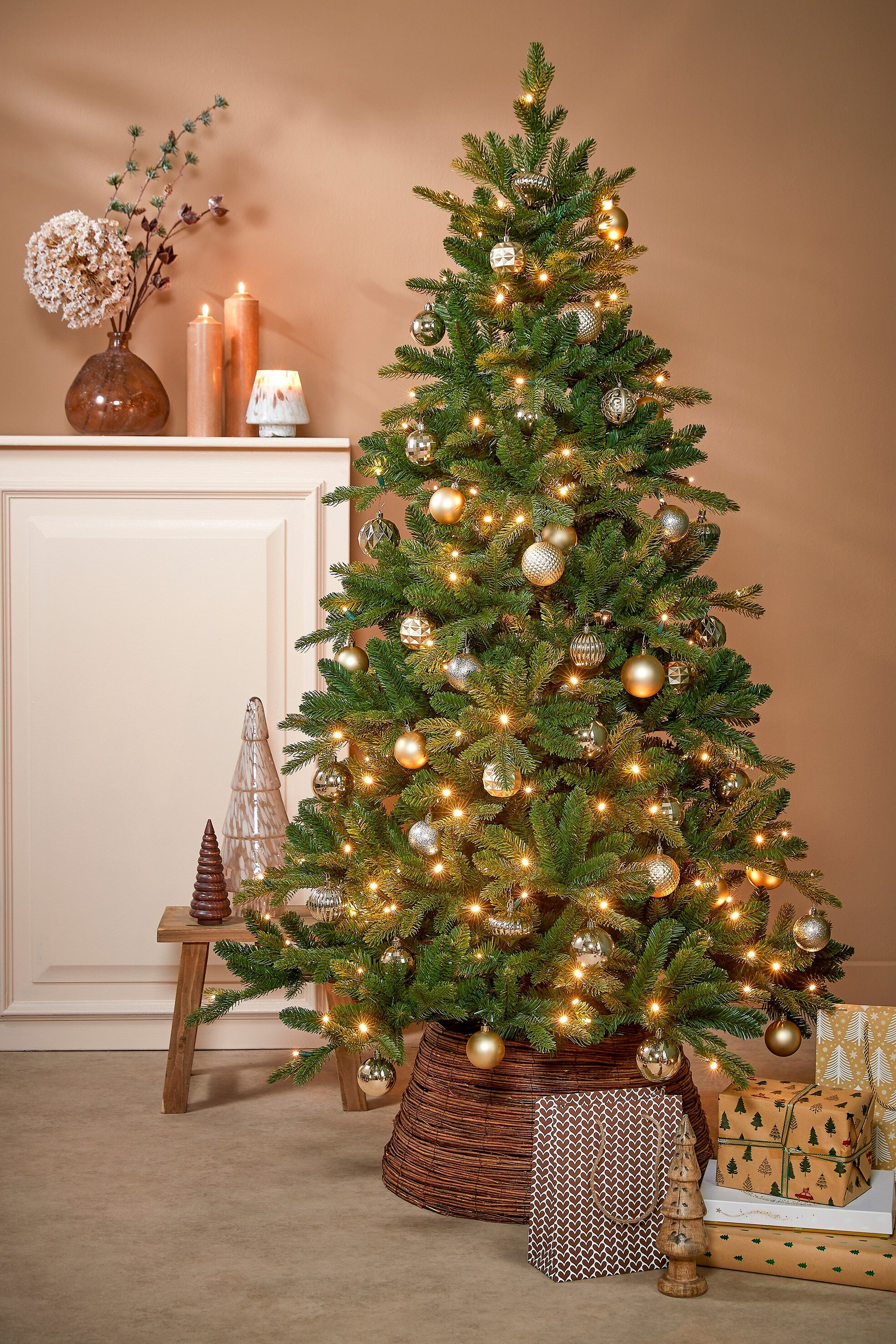 Un sapin de Noël décoré d'ornements et de lumières, des cadeaux en dessous et des bougies sur une étagère.