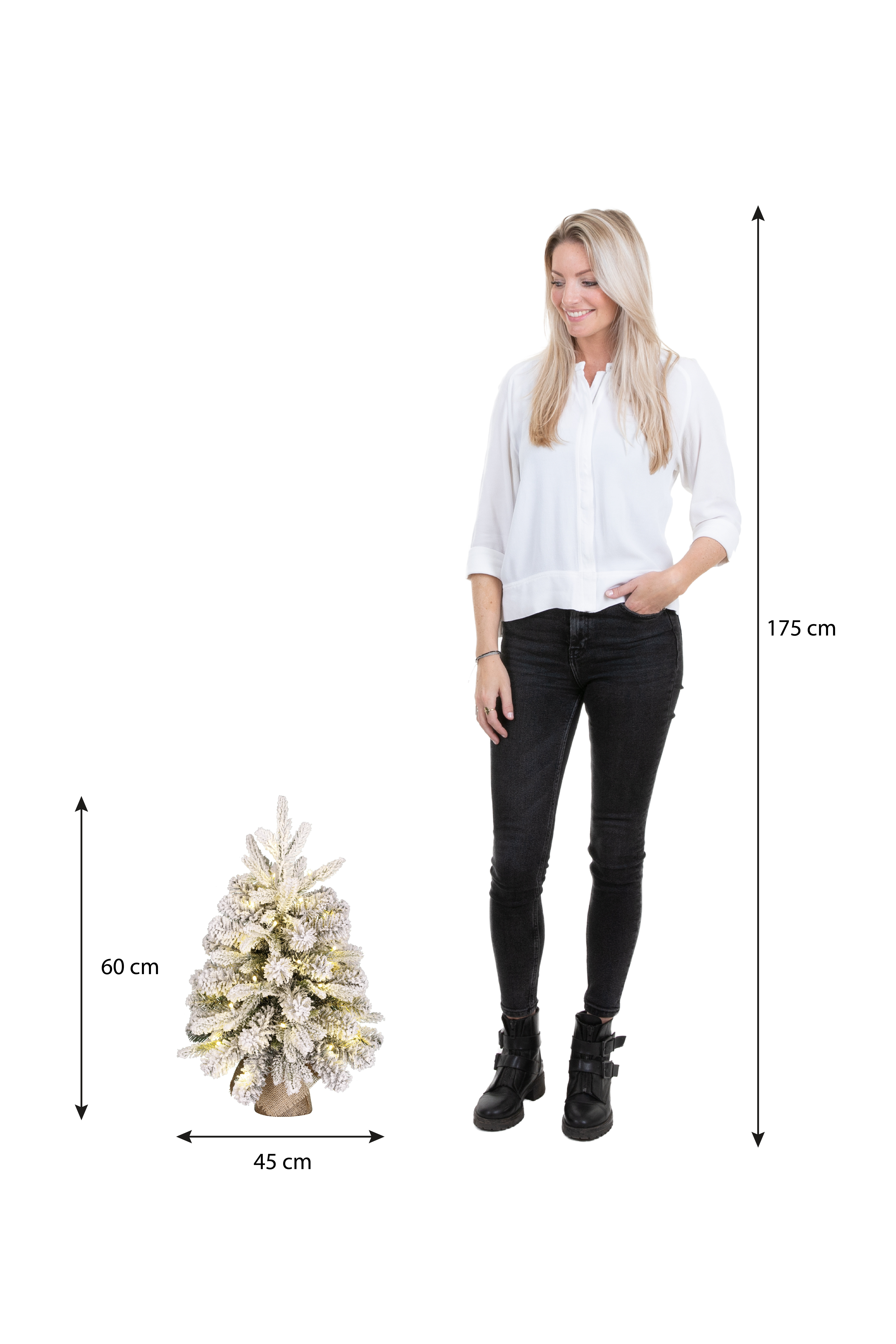 Une femme près d'un petit sapin de Noël. L'arbre est décoré de lumières. Dimensions : 60 cm, 45 cm et 175 cm.