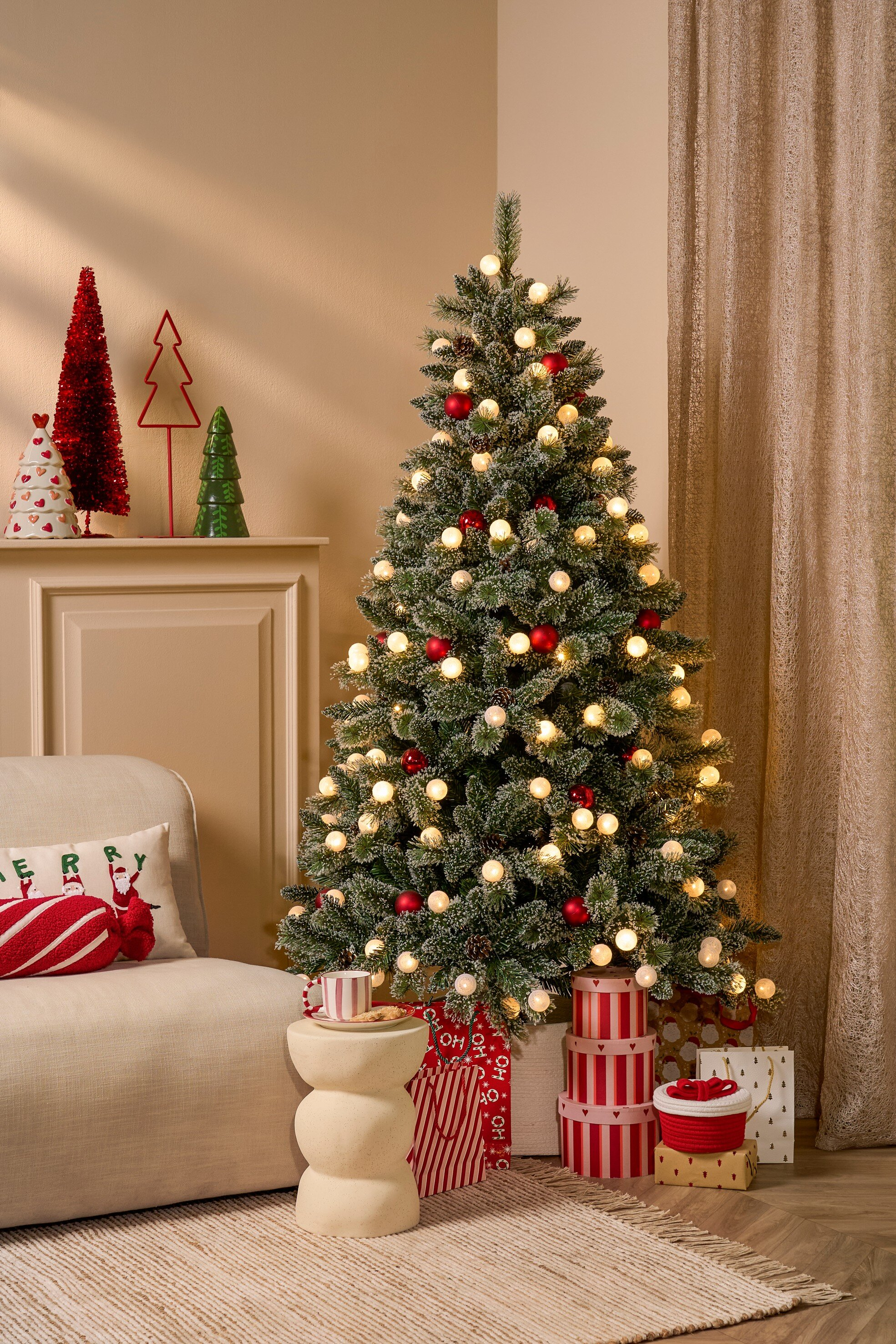 Un sapin de Noël décoré avec des lumières et des ornements. Des cadeaux et des décorations sont présents.