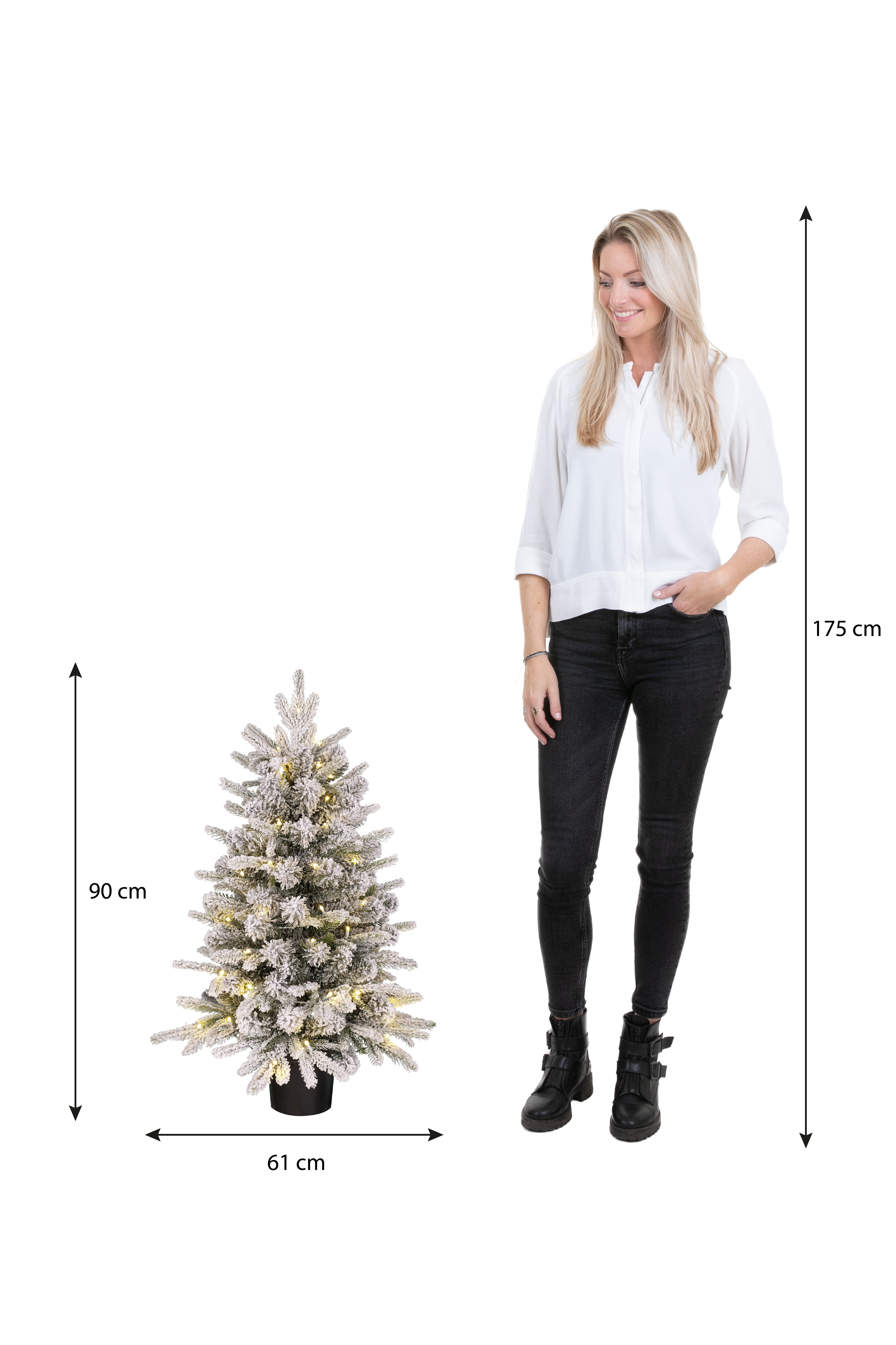 Une femme se tient à côté d'un sapin de Noël enneigé. L'arbre a des lumières et mesure 61 cm de large, 90 cm de haut. La femme mesure 175 cm.