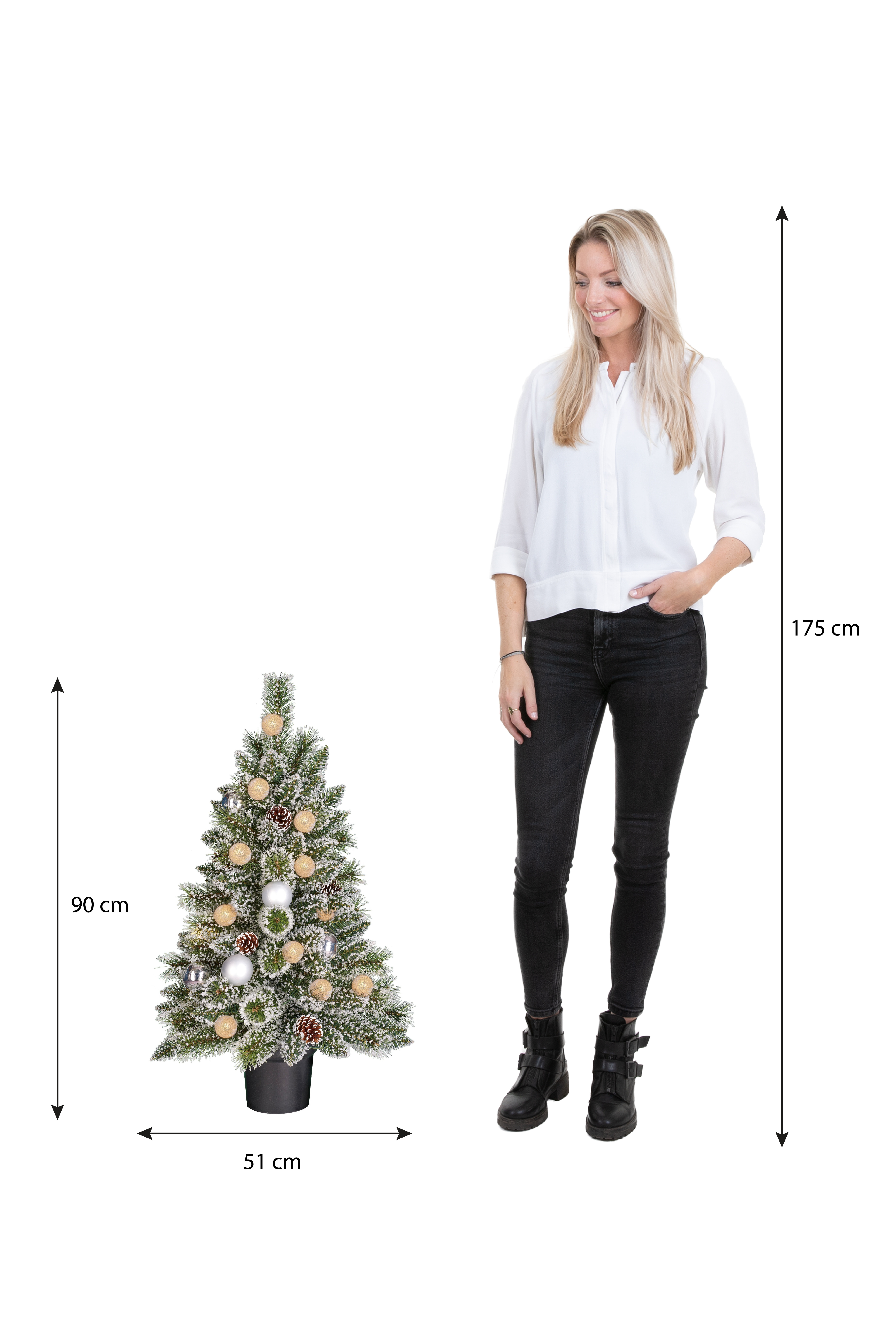 Een vrouw staat naast een versierde kerstboom. De boom is 90 cm hoog, 51 cm breed. De vrouw is 175 cm lang.