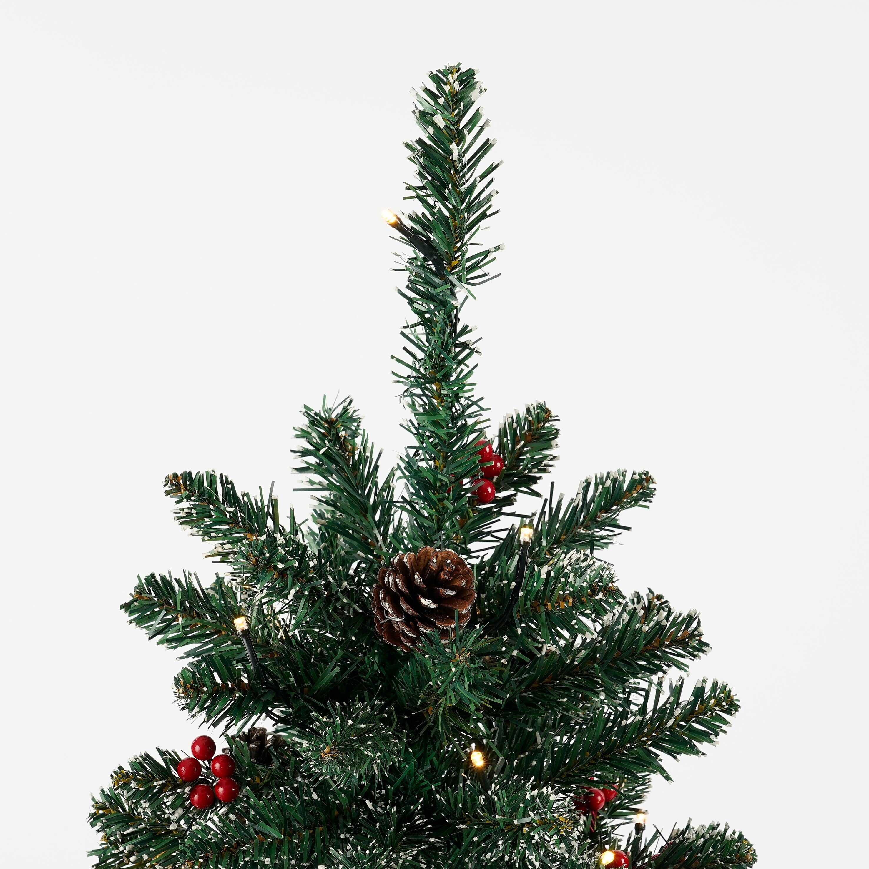 Gros plan sur le sommet d'un sapin de Noël avec une pomme de pin, des baies rouges et des lumières sur fond blanc.