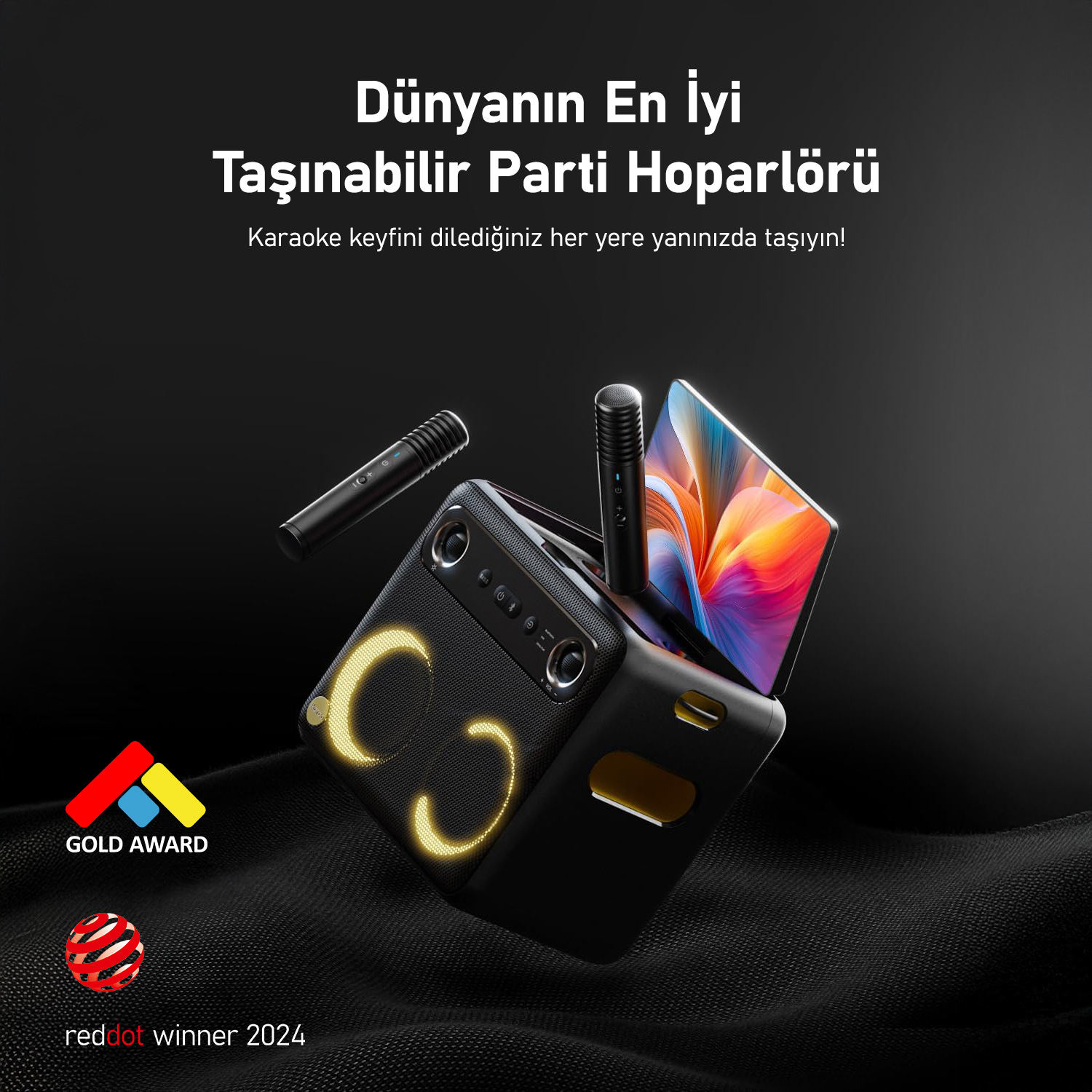 Işıklı detaylara, mikrofona ve renkli ekrana sahip siyah taşınabilir parti hoparlörü. Gold Award ve Red Dot Winner logoları görünür.