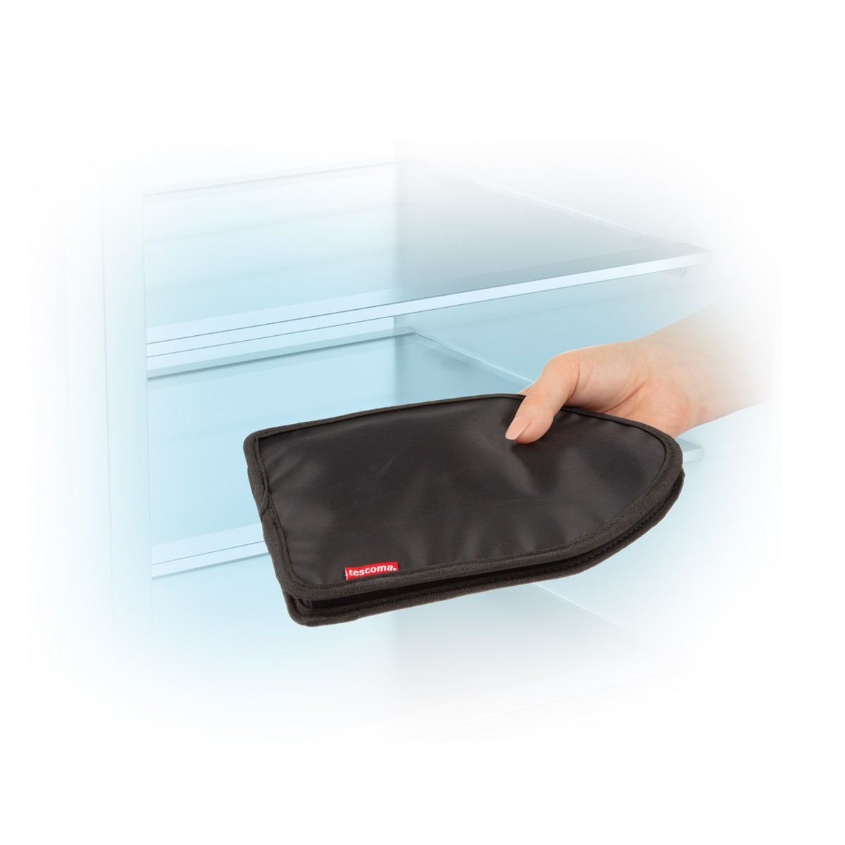 Eine Hand hält eine schwarze, mit Tescoma beschriftete Isolierbeutel in einem offenen Kühlschrank. Der Hintergrund zeigt das Innere.