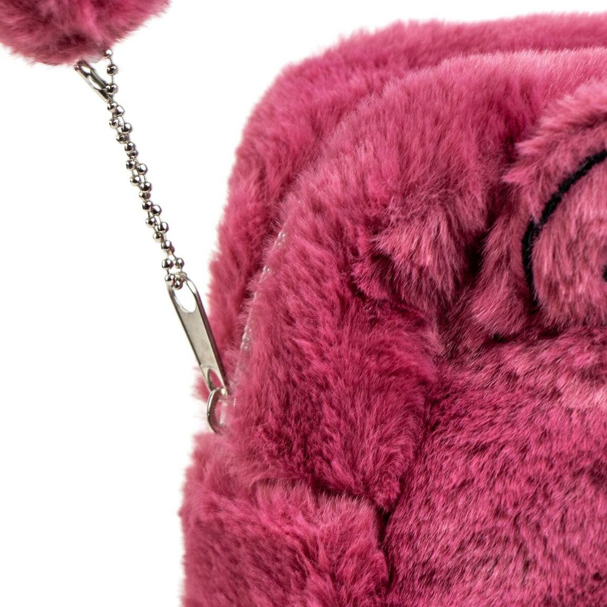 Nahaufnahme einer pinkfarbenen, flauschigen Tasche mit silberner Kette und Reißverschluss. Die Tasche hat einen Pompon.
