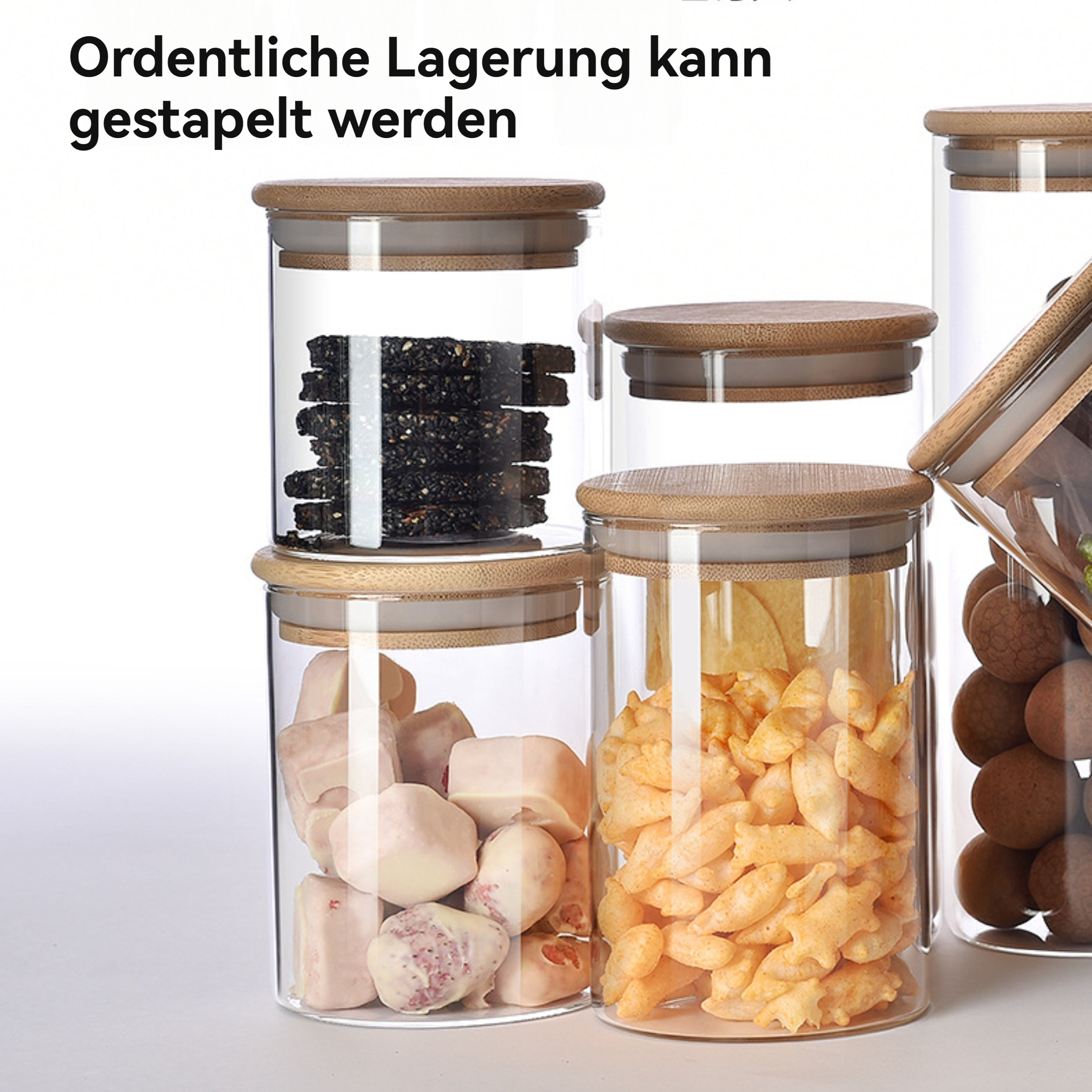 Glasbehälter mit Holzdeckeln, gefüllt mit verschiedenen Lebensmitteln: schwarzen Samen, weißen Würfeln, orangefarbenen Snacks und braunen Kugeln.