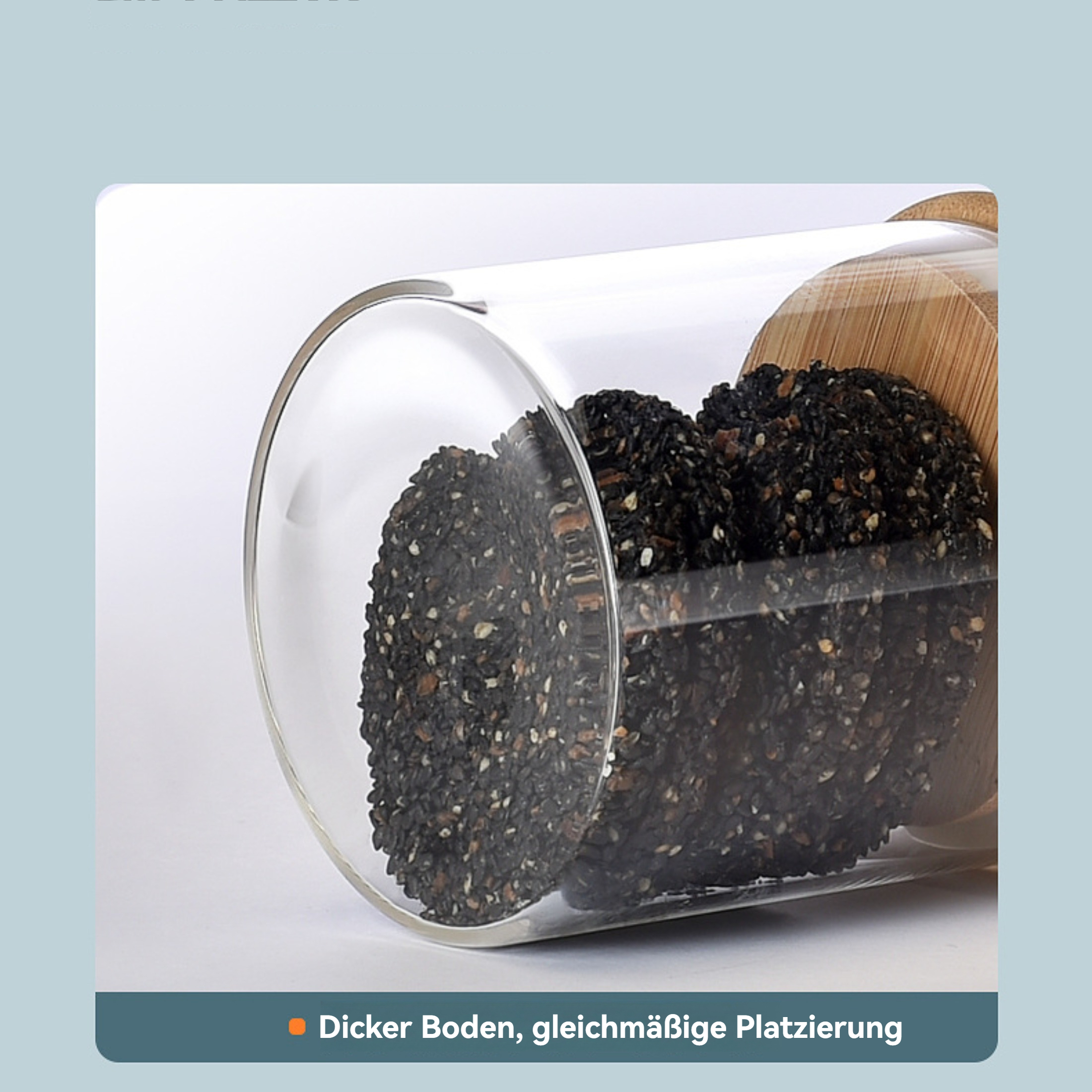 Ein Glasgefäß gefüllt mit schwarzen Samen, möglicherweise Sesam. Es hat einen Holzdeckel und steht auf weißem Grund.