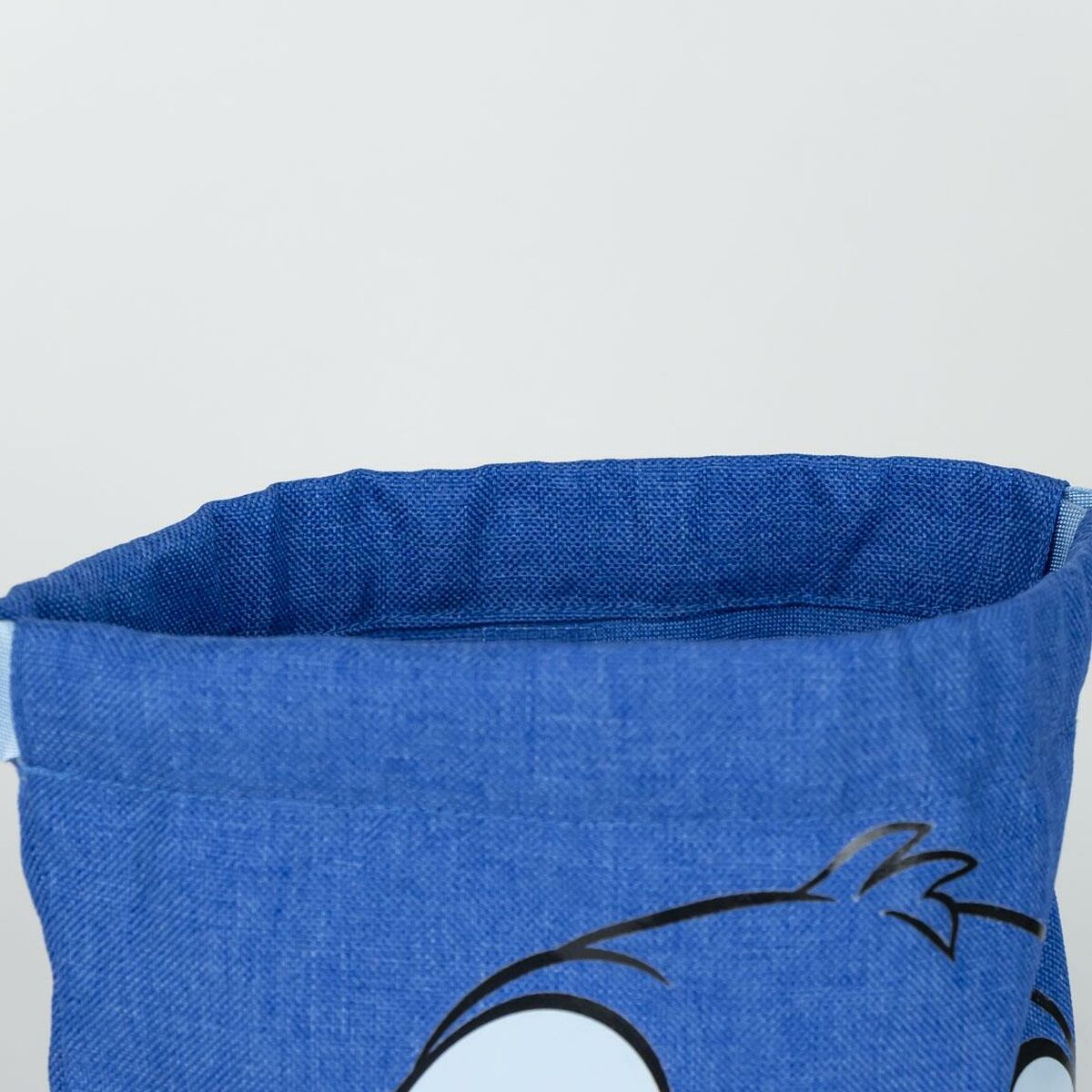 Blauer Stoffbehälter mit einer Cartoon-Figur-Umrisslinie, oben offen, vor weißem Hintergrund.