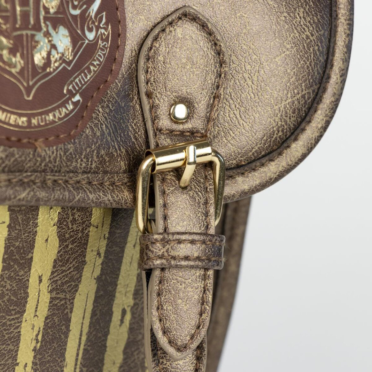 Nahaufnahme einer braunen Ledertasche mit goldener Schnalle. Die Tasche hat ein Wappen und gelbe Streifen.