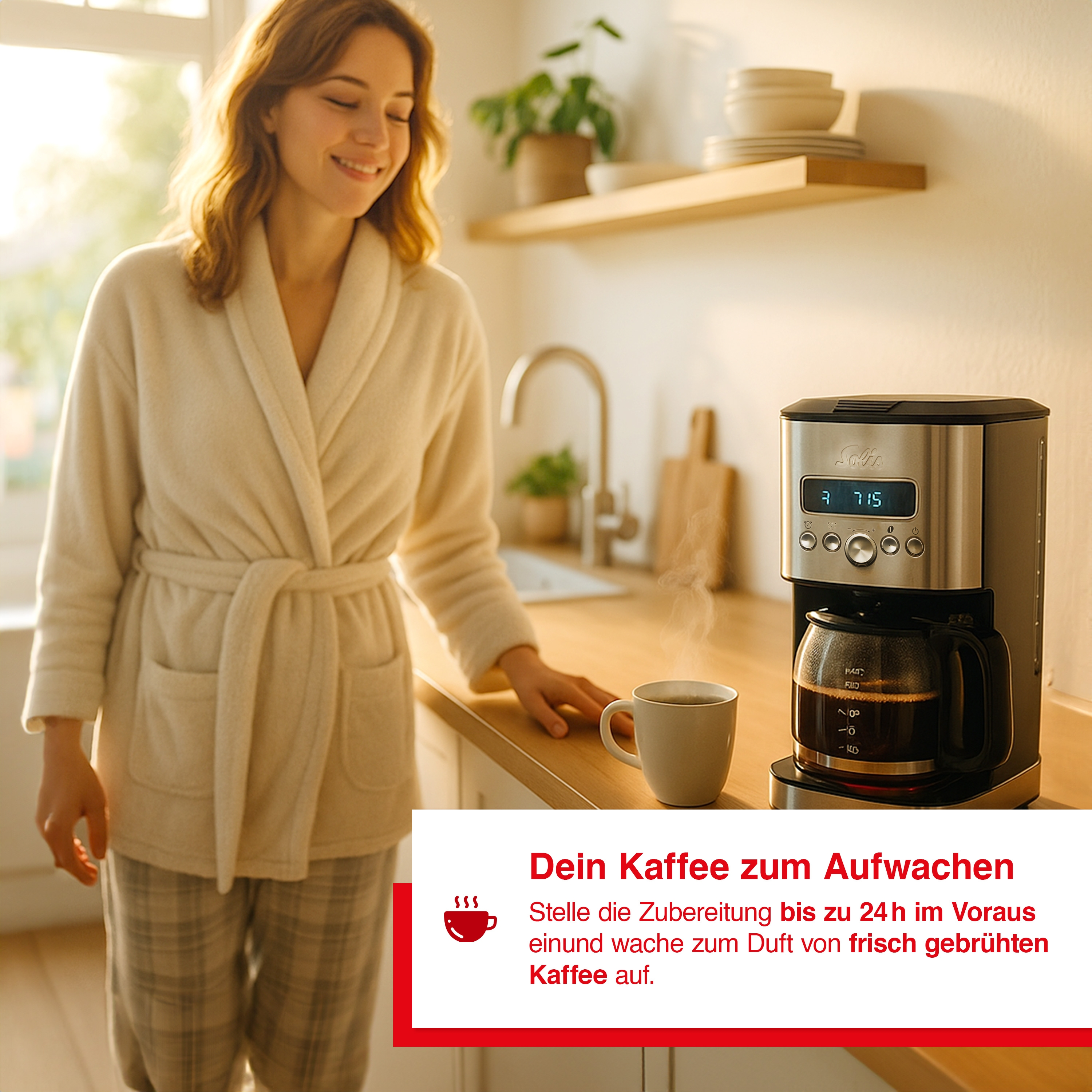 Frau im Bademantel lächelt in der Nähe der Kaffeemaschine. Eine Tasse Kaffee steht auf der Theke. Sonnenlicht scheint in die Küche.