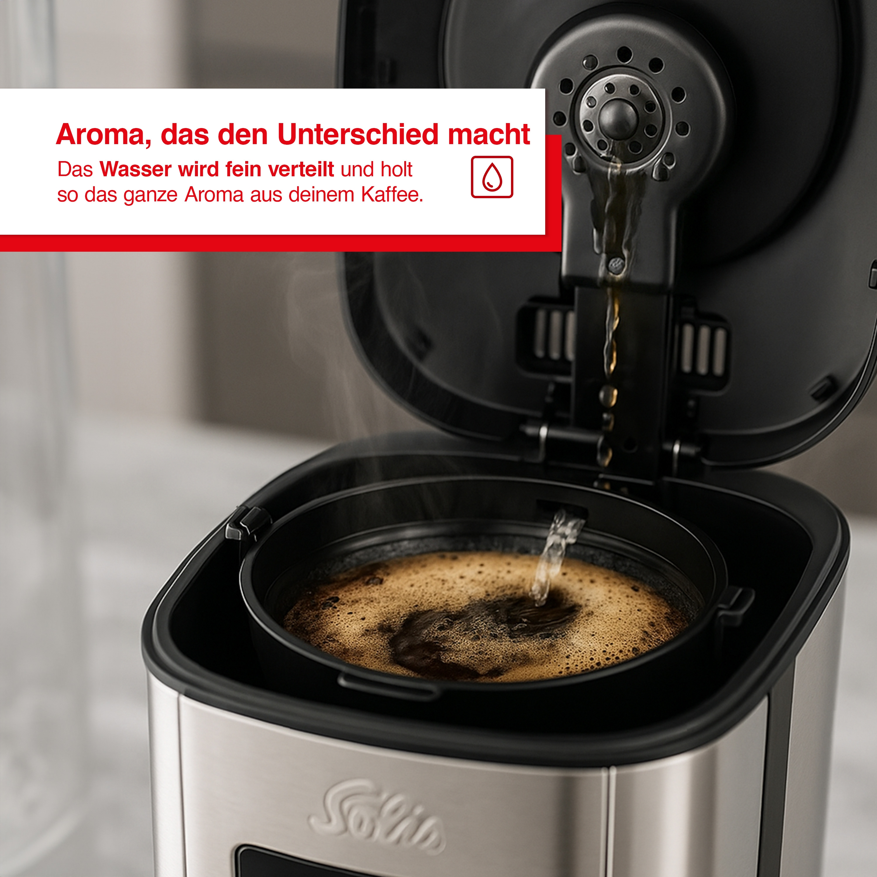 Eine Kaffeemaschine brüht Kaffee. Wasser gießt über Kaffeepulver. Dampf steigt auf. Text auf Deutsch ist sichtbar.