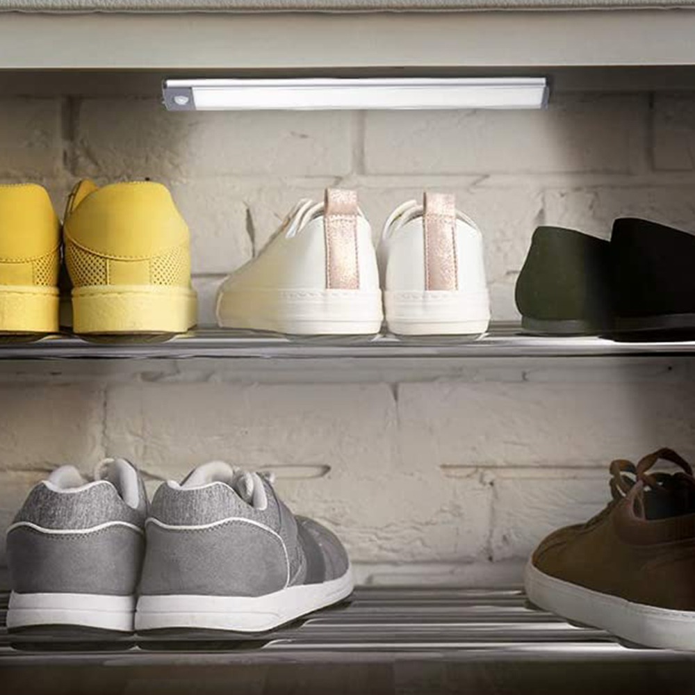 Schuhe auf Regalen. Gelbe, weiße, schwarze und graue Schuhe. Hintergrund Ziegelmauer und eine Leuchte über den Schuhen.