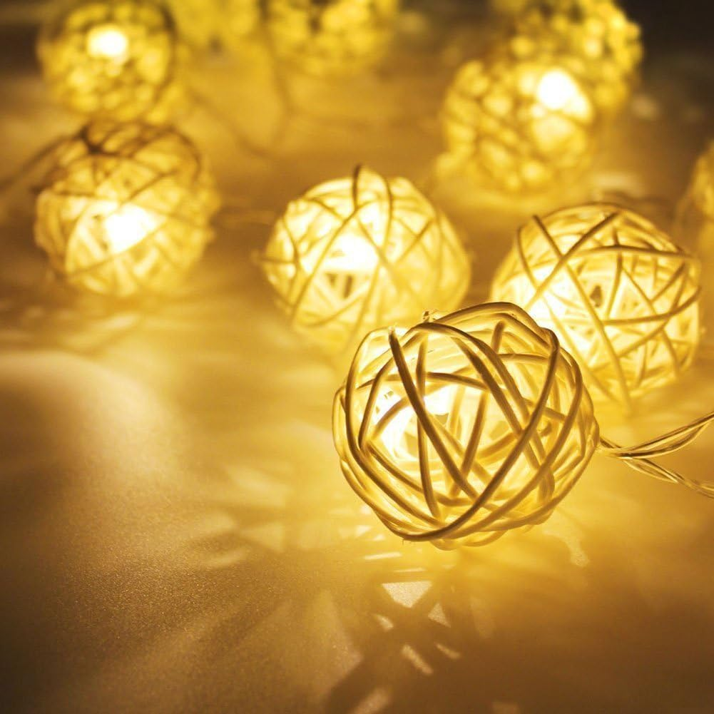 Nahaufnahme von leuchtenden, gewebten Kugellichtern. Warmes gelbes Licht erzeugt Schatten. Mehrere Lichter im Fokus, einige im Hintergrund unscharf.