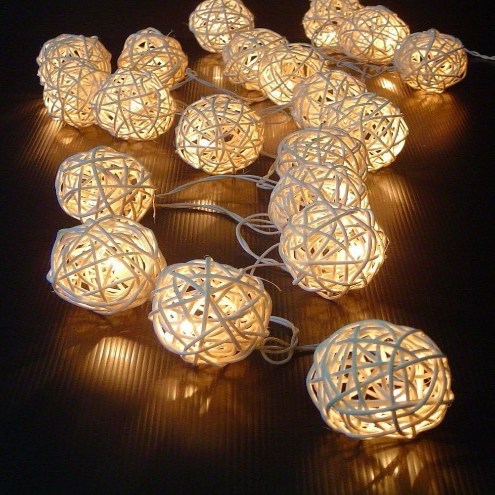 Lichterkette mit weißen gewebten Kugeln, die vor dunklem Hintergrund warm leuchten und eine gemütliche Atmosphäre schaffen.