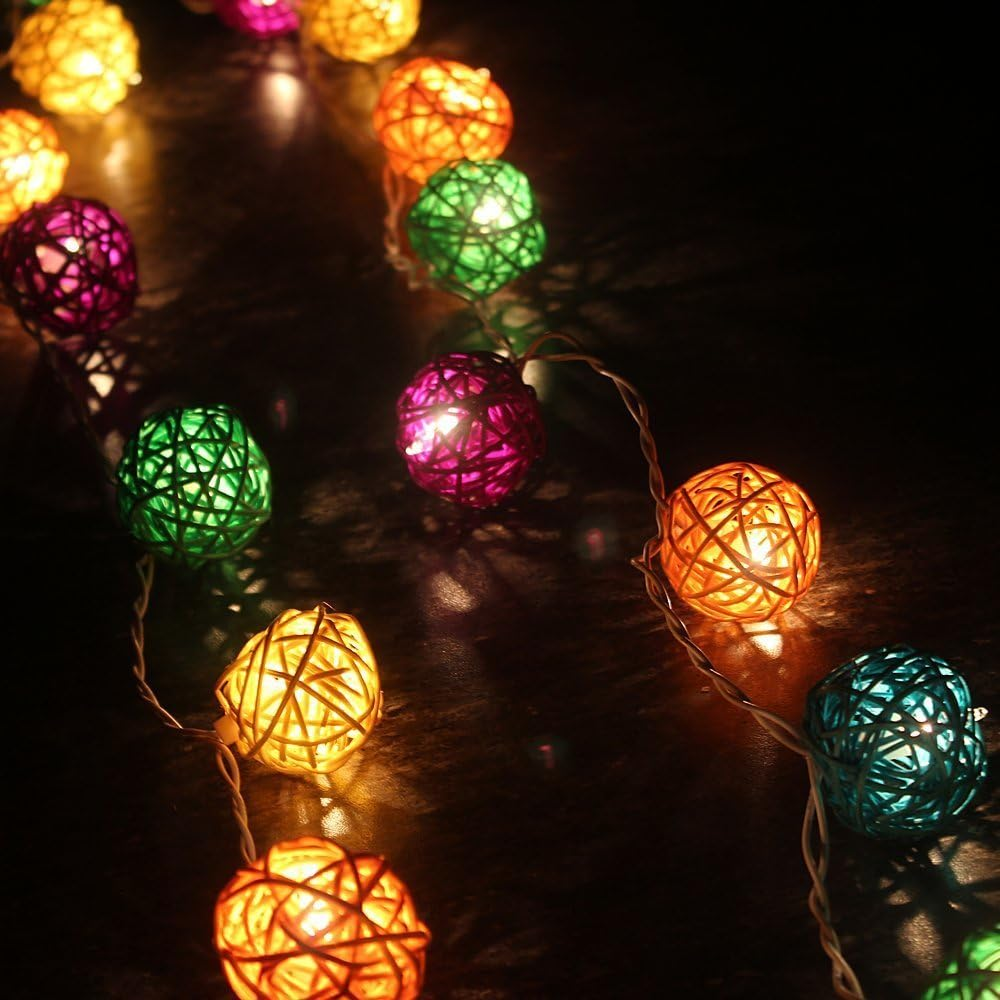 Lichterketten mit bunten gewebten Kugeln beleuchten eine dunkle Oberfläche. Verschiedene Farben: Gelb, Orange, Grün, Lila und Blau.