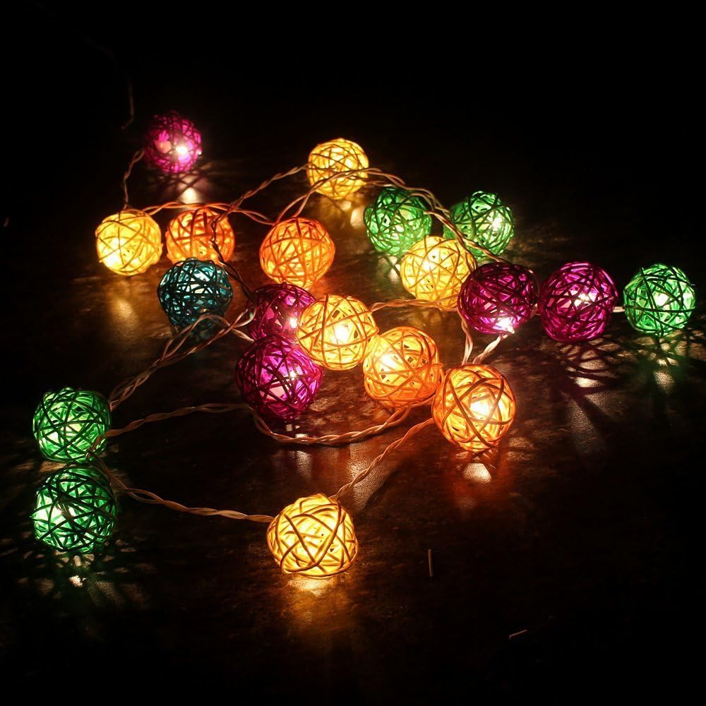 Lichterkette mit bunten, gewebten Kugeln. Die Kugeln sind beleuchtet und erzeugen ein warmes Leuchten vor dunklem Hintergrund. Farben sind Grün, Orange und Lila.