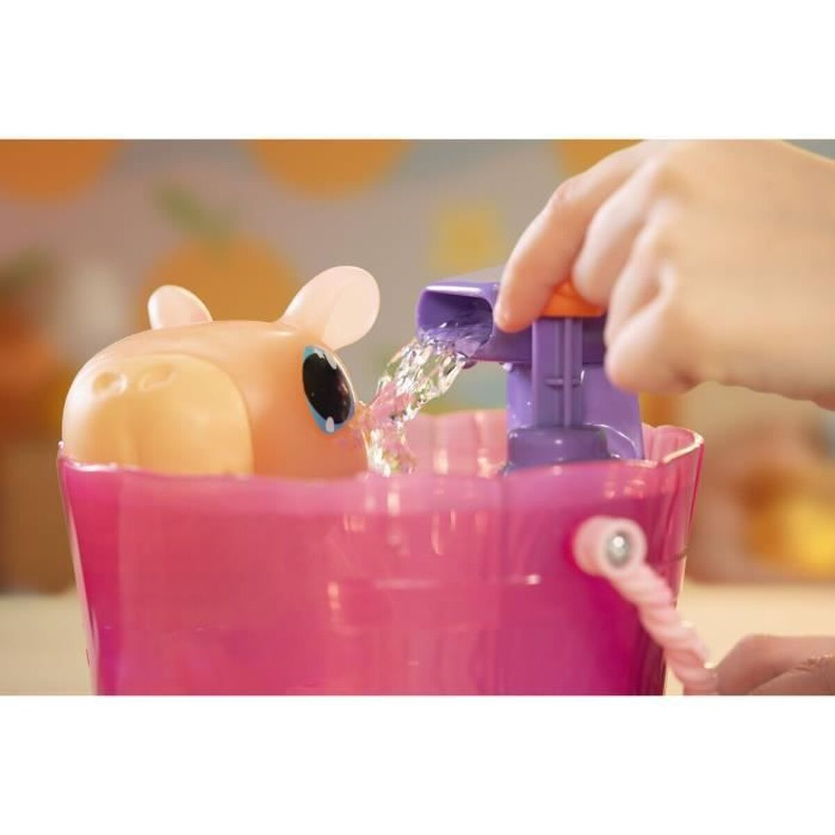 Eine Kinderhand gießt Wasser aus einem lila Ausguss in einen rosa Eimer mit einem Spielzeugpferd. Das Pferd hat große Augen und Ohren.