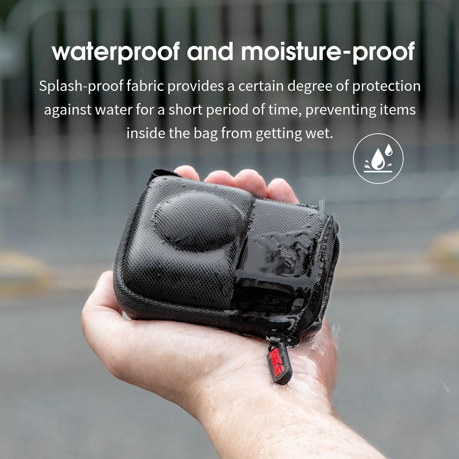 Una mano tiene in mano una borsa nera con cerniera rossa, goccioline d'acqua visibili. Testo: impermeabile e resistente all'umidità.