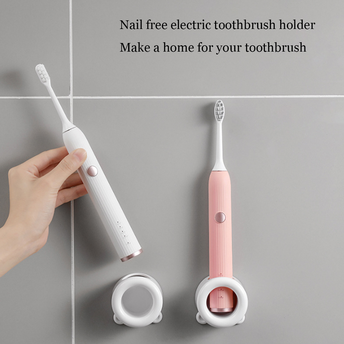 Zwei elektrische Zahnbürsten, weiß und rosa, mit Haltern an einer grauen Wand. Eine wird von einer Hand gehalten. Text oben.