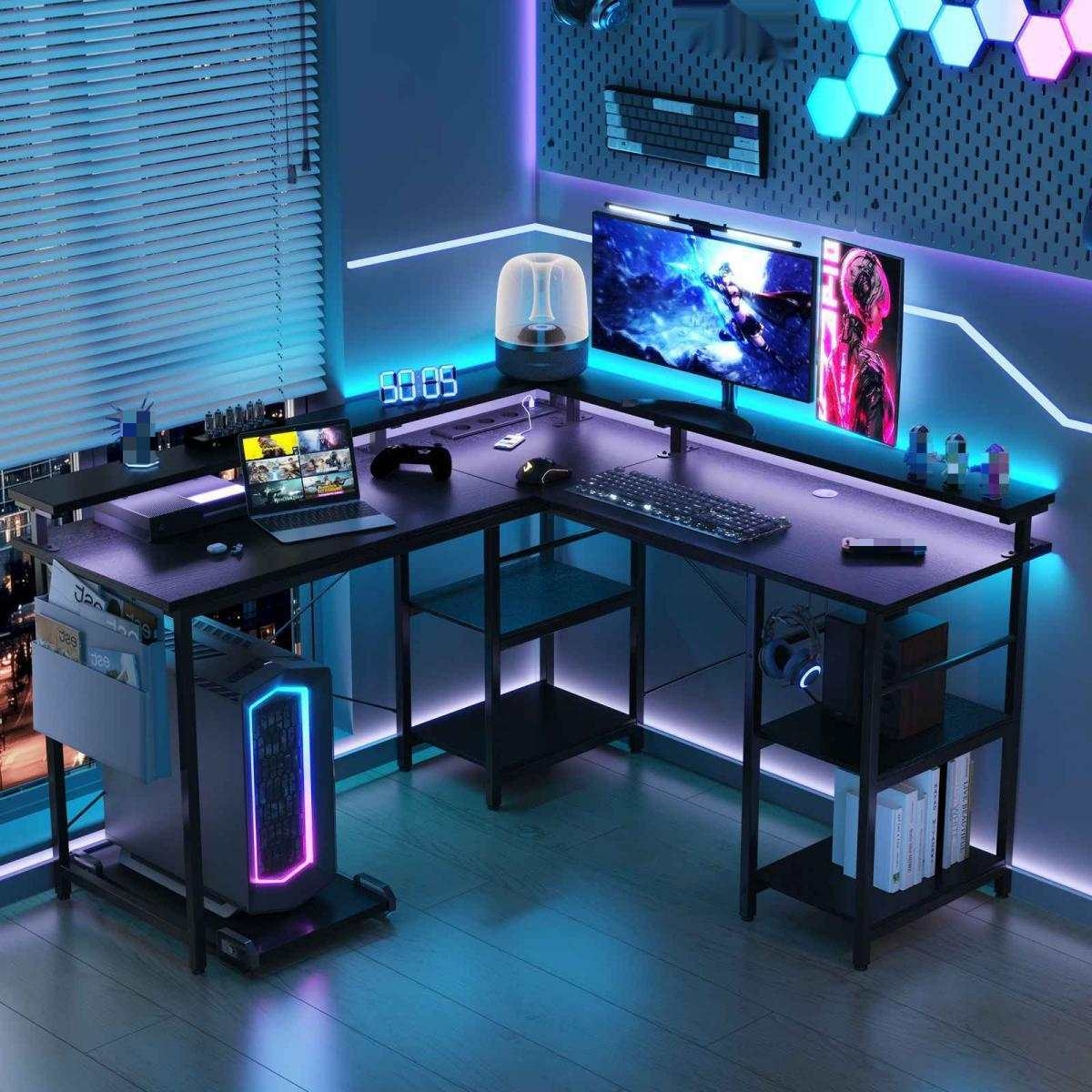 Gaming-Setup mit schwarzem L-förmigen Schreibtisch, zwei Monitoren, PC, Tastatur und Laptop. Blaue und violette LED-Leuchten beleuchten den Raum.