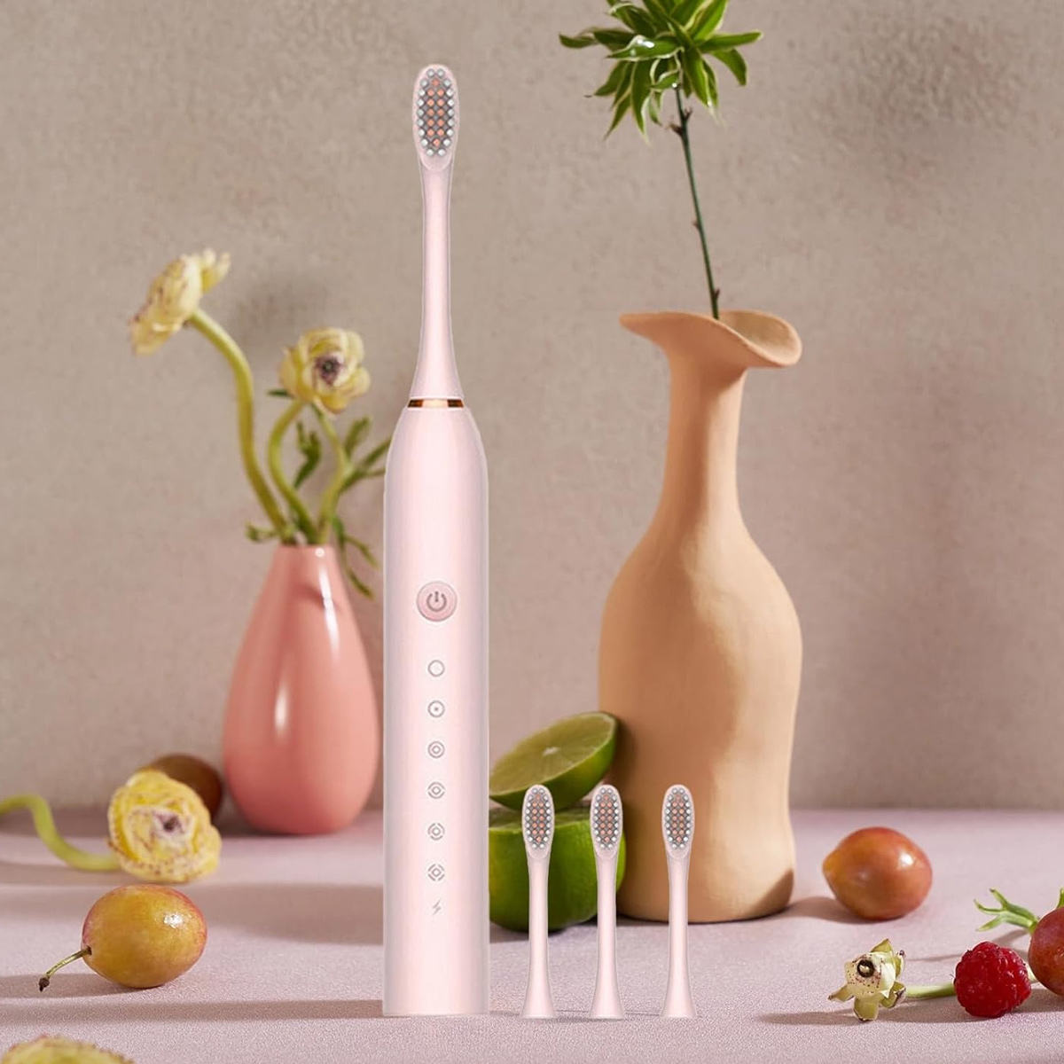 Eine rosa elektrische Zahnbürste mit Ersatzköpfen, Limetten und Vasen mit Blumen auf einem Tisch.