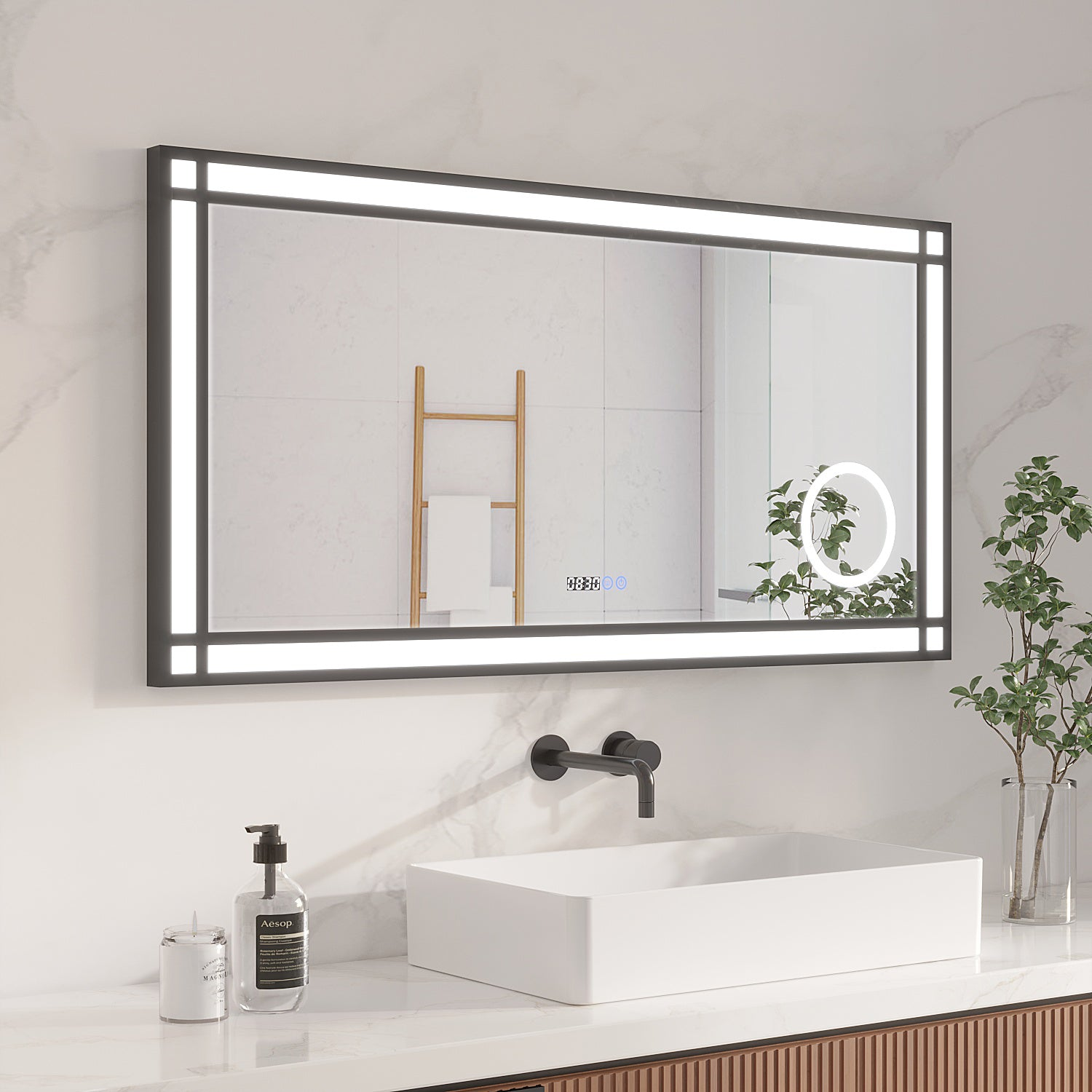 Badezimmer mit großem, rechteckigem Spiegel mit Lichtern. Ein weißes Waschbecken, Wasserhahn und Pflanzen sind davor. Eine Holzleiter ist dahinter.