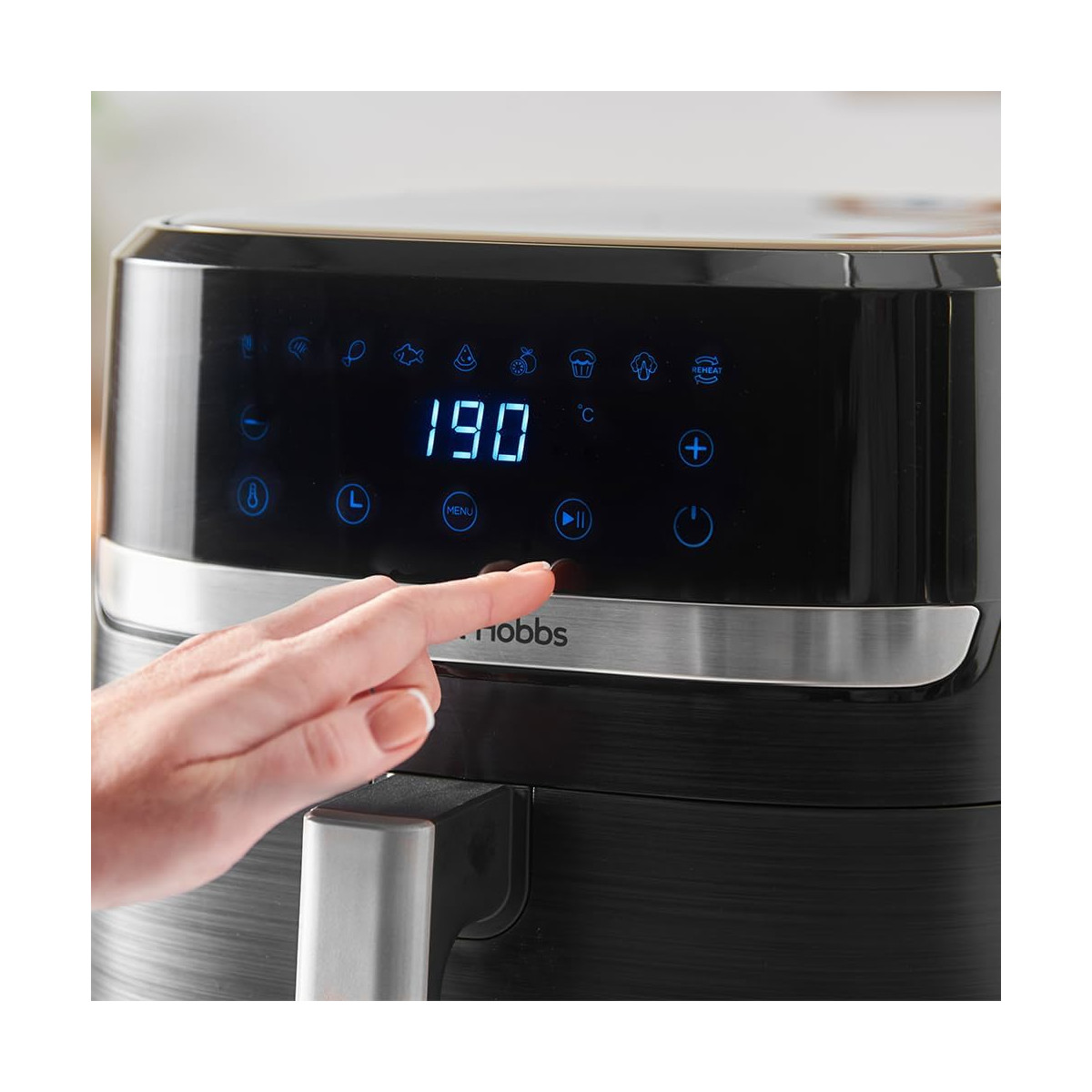 Eine Hand drückt die Starttaste eines schwarzen Air Fryers. Das Display zeigt 190 Grad. Der Air Fryer ist von Hobbs.