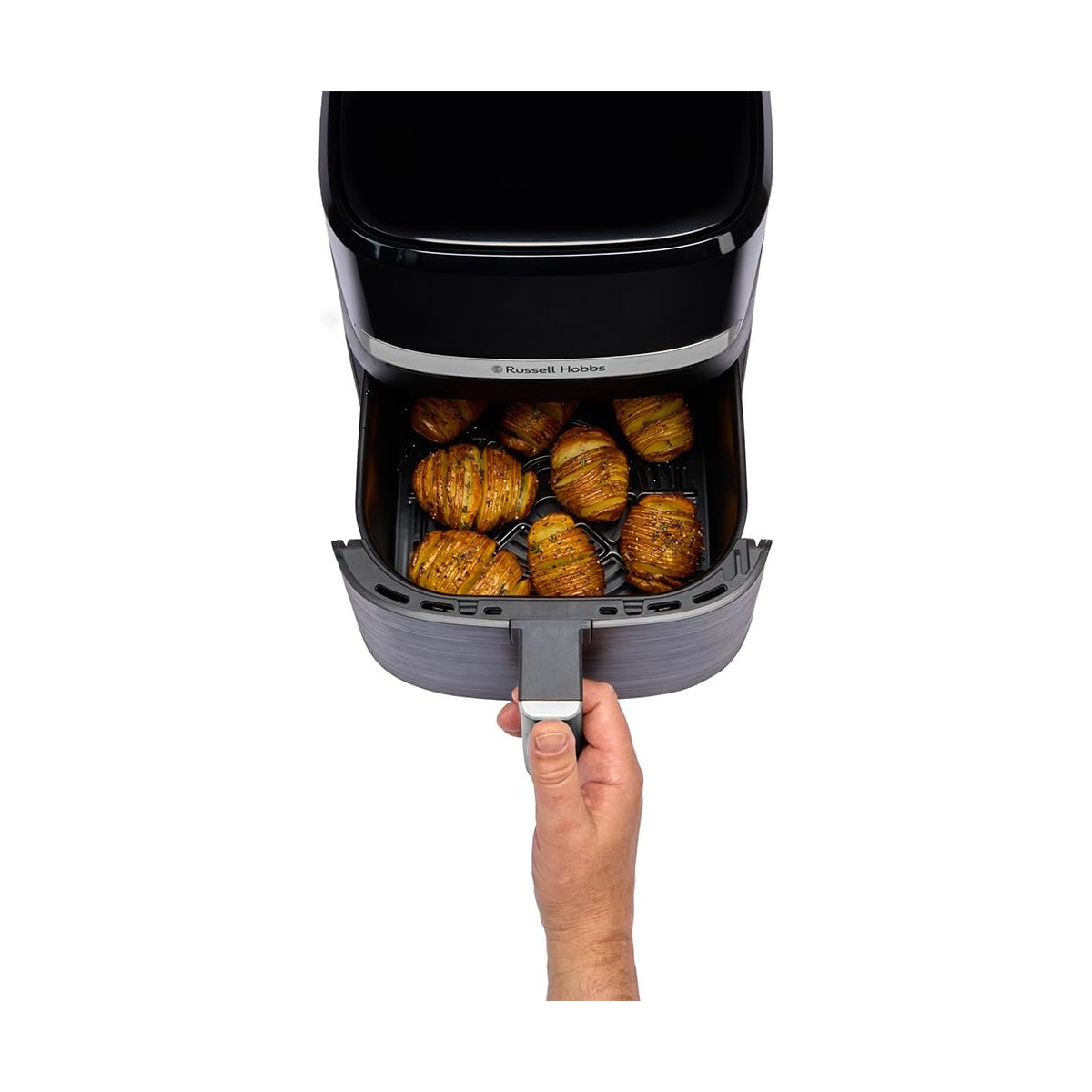 Eine Heißluftfritteuse mit Bratkartoffeln. Eine Hand zieht den Korb heraus. Die Fritteuse ist schwarz und grau, mit einem Russell Hobbs Logo.