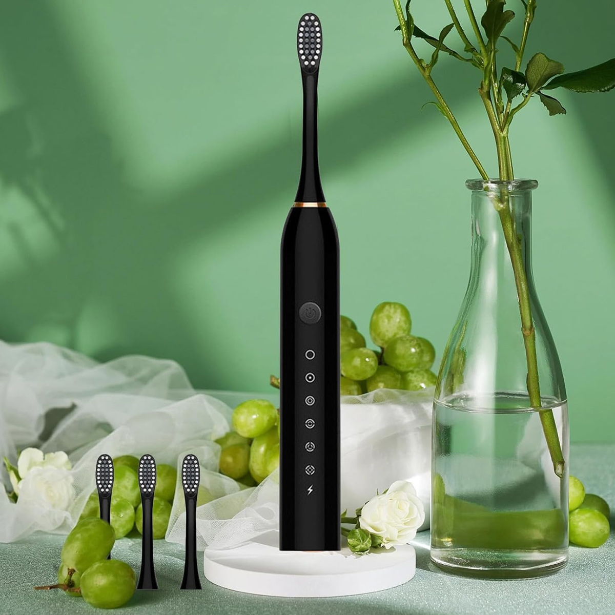 Schwarze elektrische Zahnbürste mit drei zusätzlichen Köpfen, Trauben, Blumen und einer Vase mit einer Pflanze auf grünem Hintergrund.