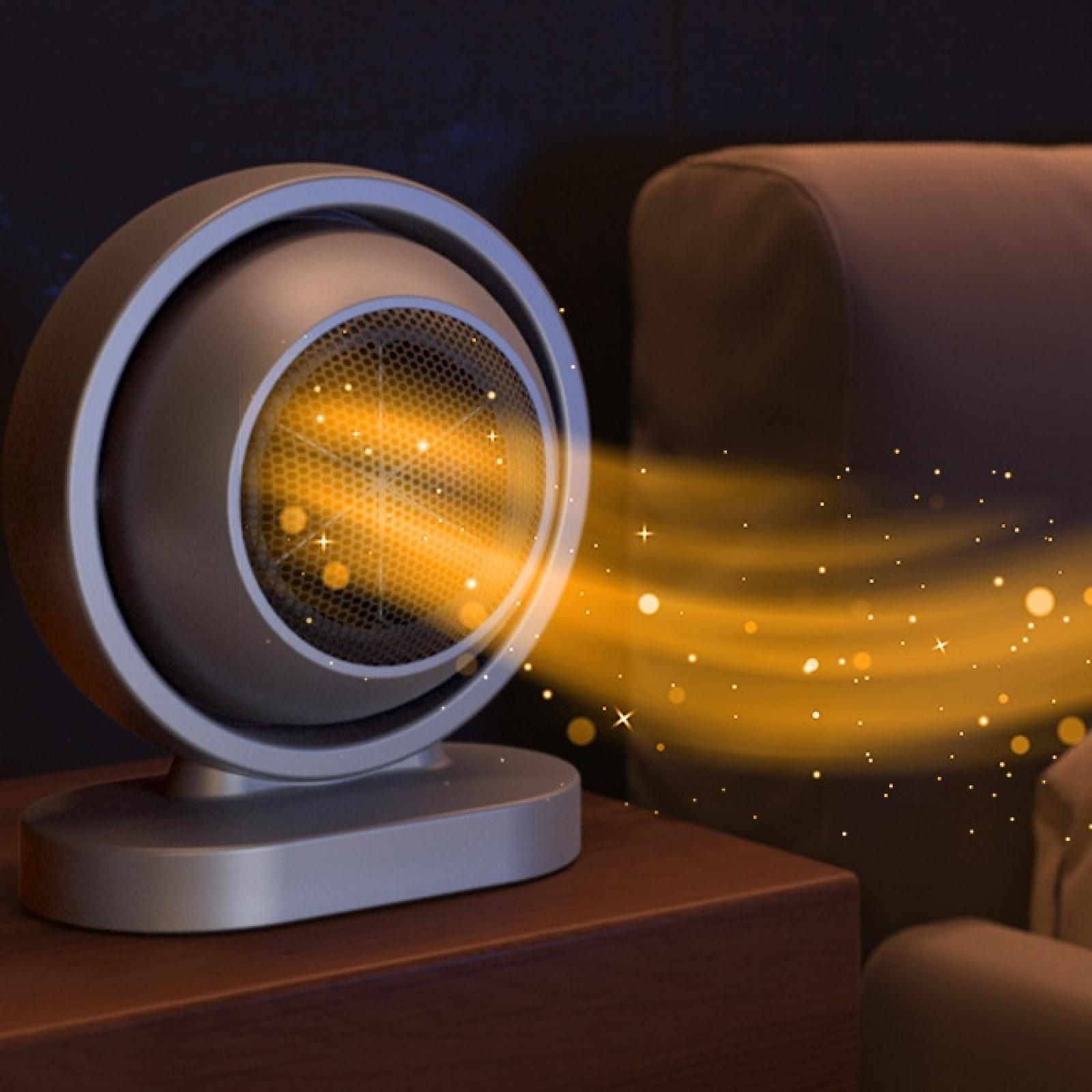 Ein kleiner grauer Heizlüfter strahlt orangefarbenes Licht und Glitzer aus. Er steht auf einem Holztisch, im Hintergrund eine braune Couch.