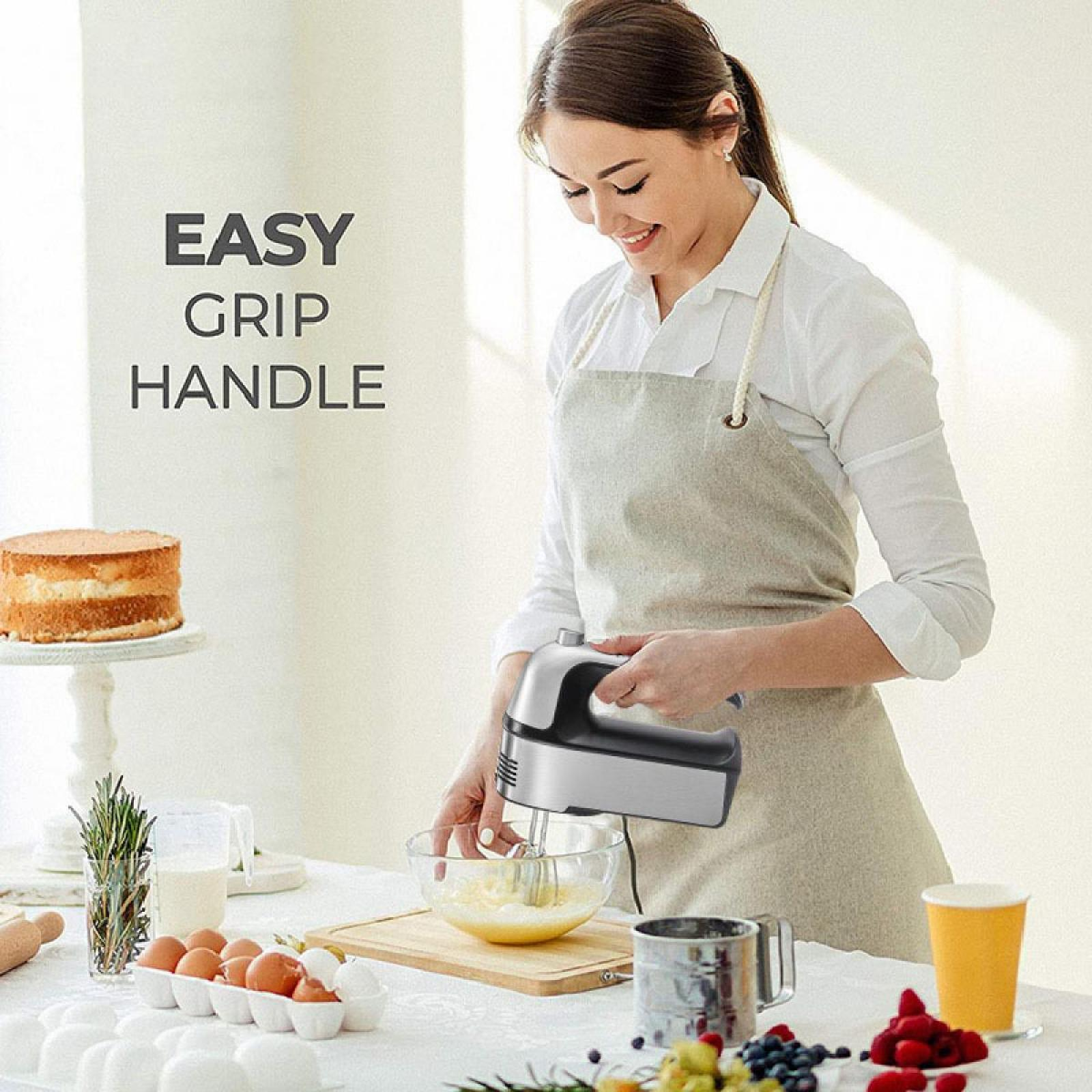 Eine Frau benutzt einen Mixer. Auf dem Tisch befinden sich ein Kuchen, Eier und Zutaten. Der Text lautet: EASY GRIP HANDLE.