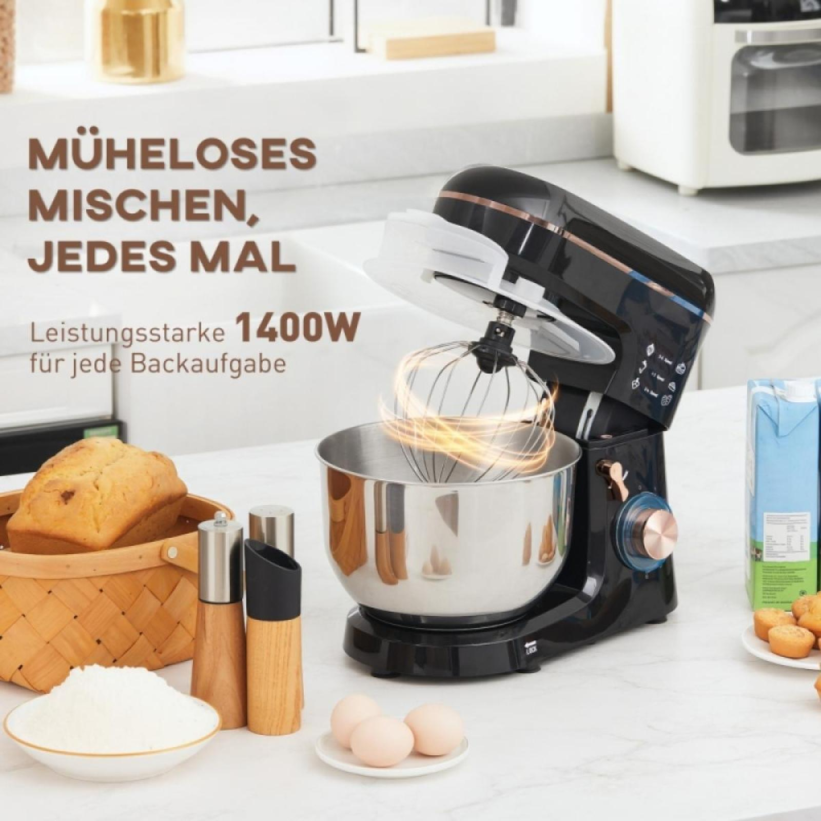 Ein schwarzer Küchenmixer mit Edelstahlschüssel. Zutaten und Backwaren im Vordergrund.