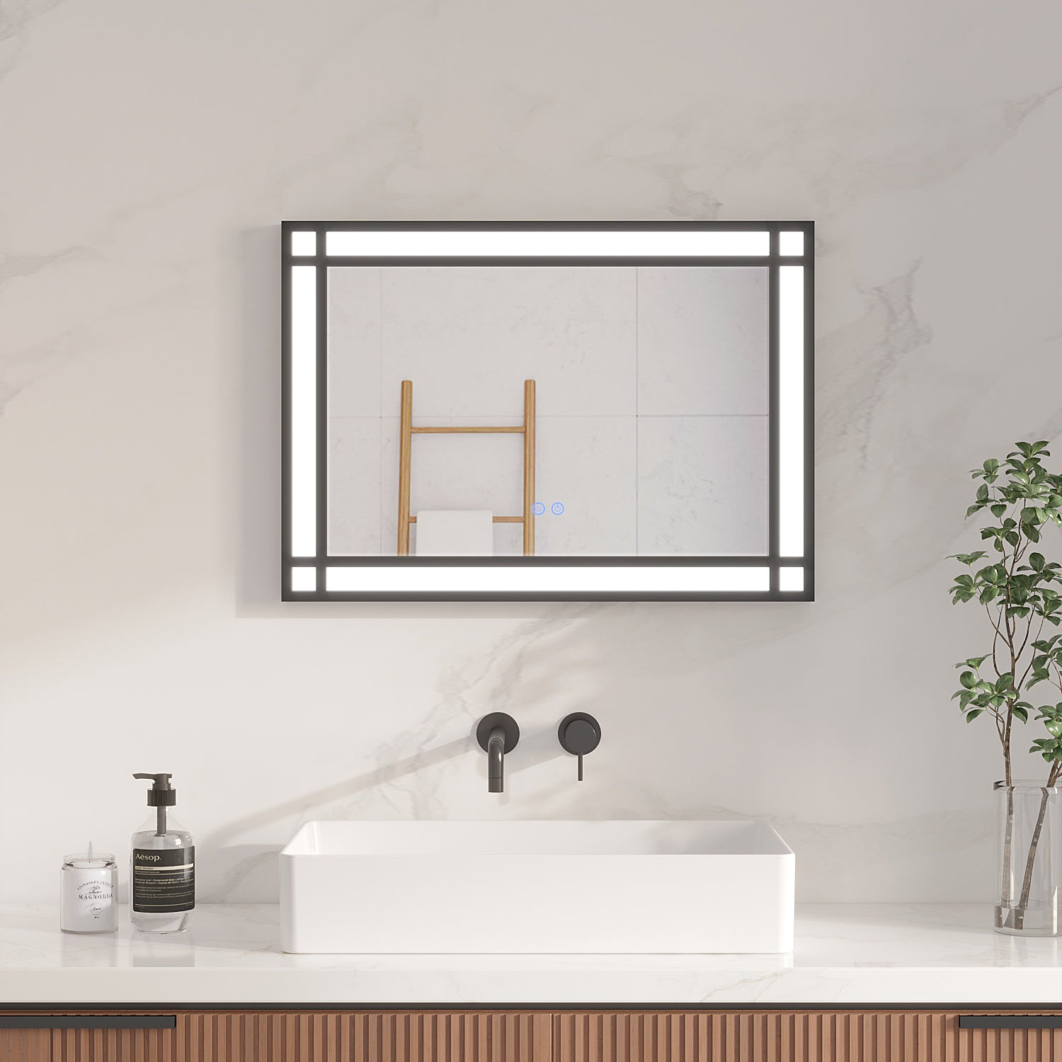 Badezimmer mit beleuchtetem Spiegel, Waschbecken, Wasserhahn, Seifenspender, Kerze und Pflanze. Ein Holzhandtuchhalter spiegelt sich im Spiegel.