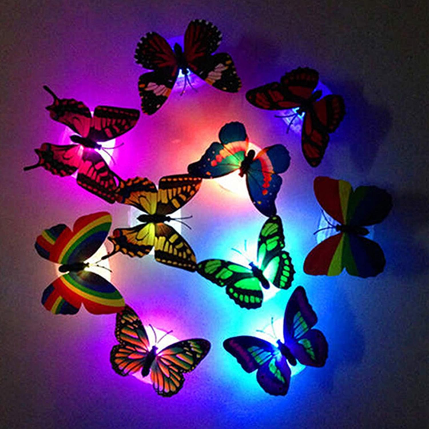 Bunte Schmetterlingslichter an einer Wand. Schmetterlinge haben verschiedene Muster und Farben. Der Hintergrund hat lila und blaues Licht.