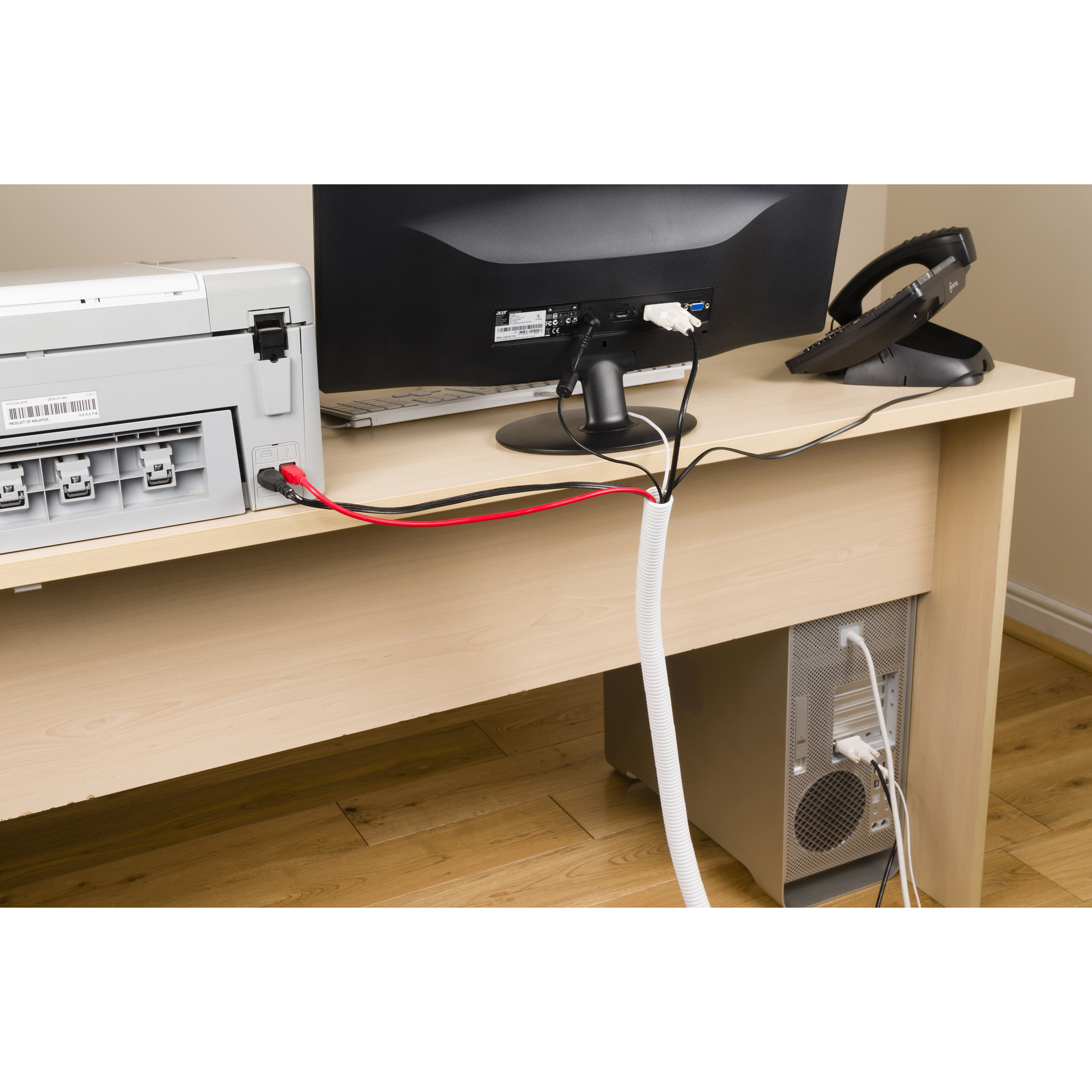 Scrivania con stampante, monitor, telefono e computer. Cavi gestiti con condotto bianco. Pavimento in legno.