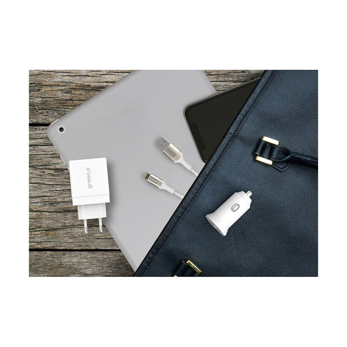 Ein Tablet, Telefon, Ladegerät und Kabel befinden sich in der Nähe einer dunkelblauen Tasche. Ein Autoladegerät ist ebenfalls sichtbar.