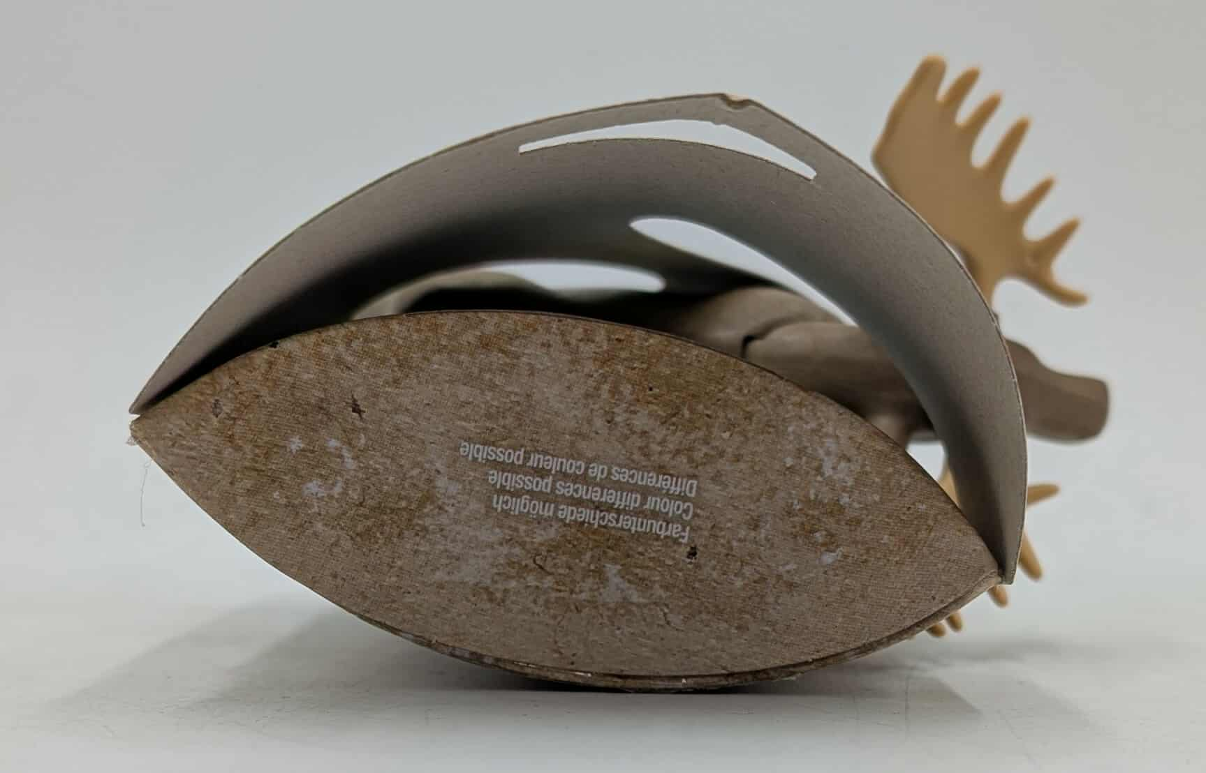 Eine Elchfigur, umgeben von Kartonverpackung mit Text. Geweih ist sichtbar. Der Hintergrund ist weiß.