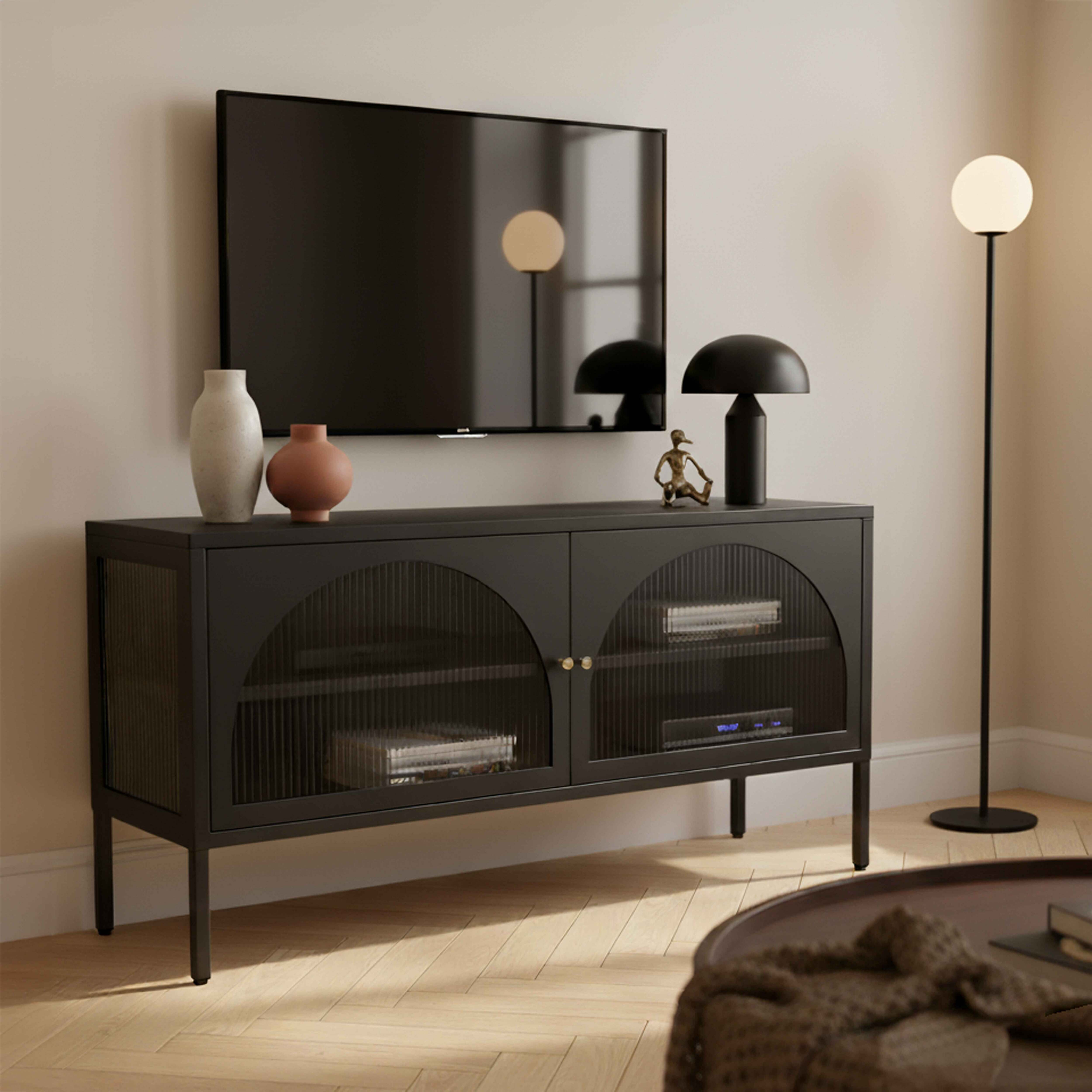 Ein modernes Wohnzimmer mit einem schwarzen TV-Ständer, Fernseher, Stehlampe und Couchtisch.