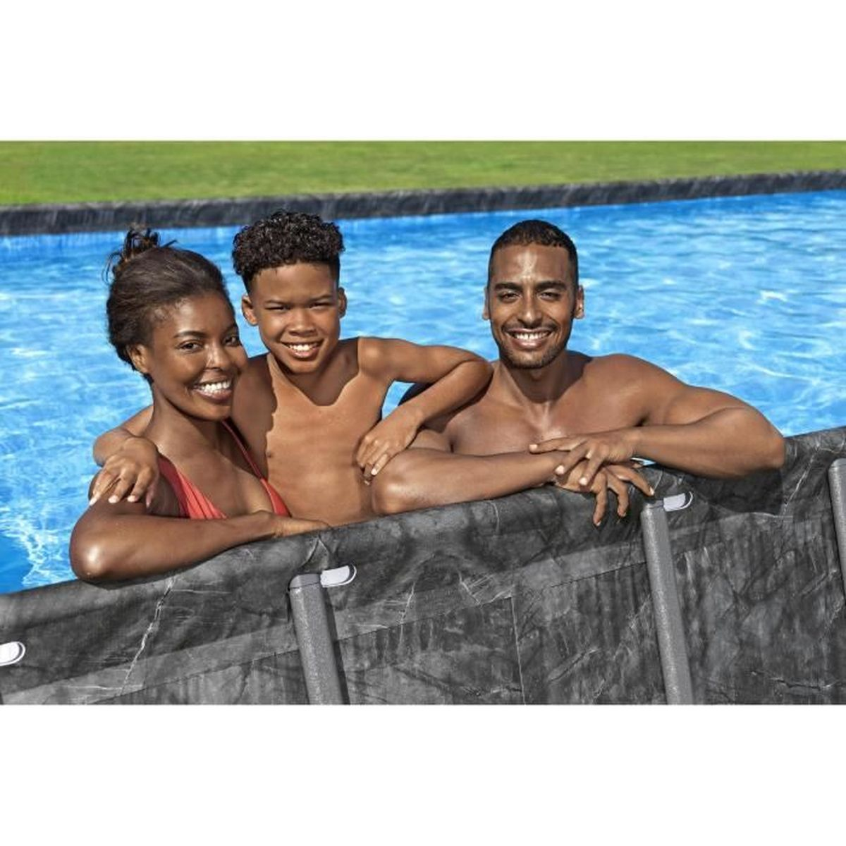 Tre persone in piscina sorridono alla fotocamera. Una donna con un top rosso e due uomini, tutti con la pelle scura, si appoggiano al bordo.
