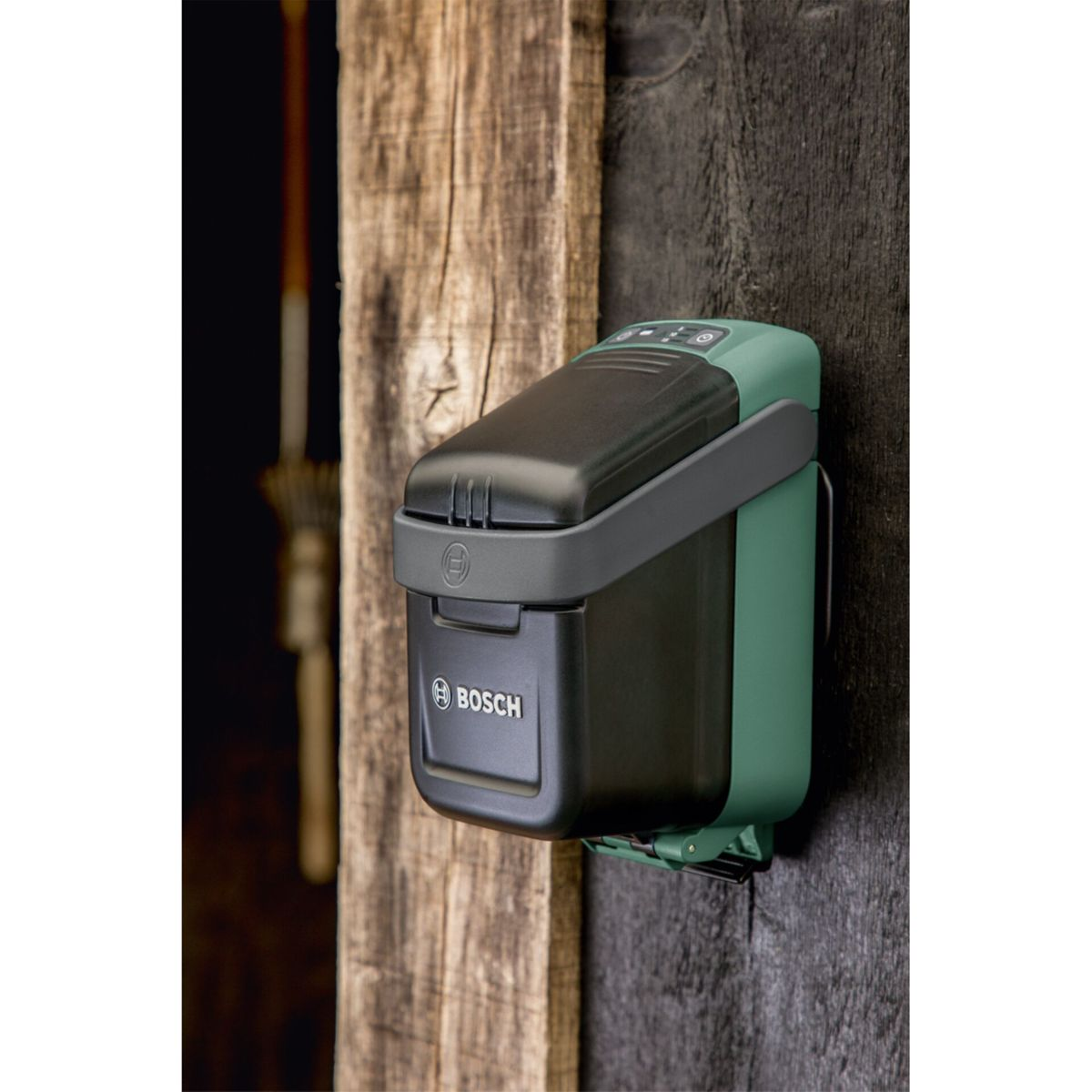 Zielono-czarne urządzenie Bosch jest zamontowane na drewnianej ścianie. Urządzenie posiada pokrywę i logo Bosch.