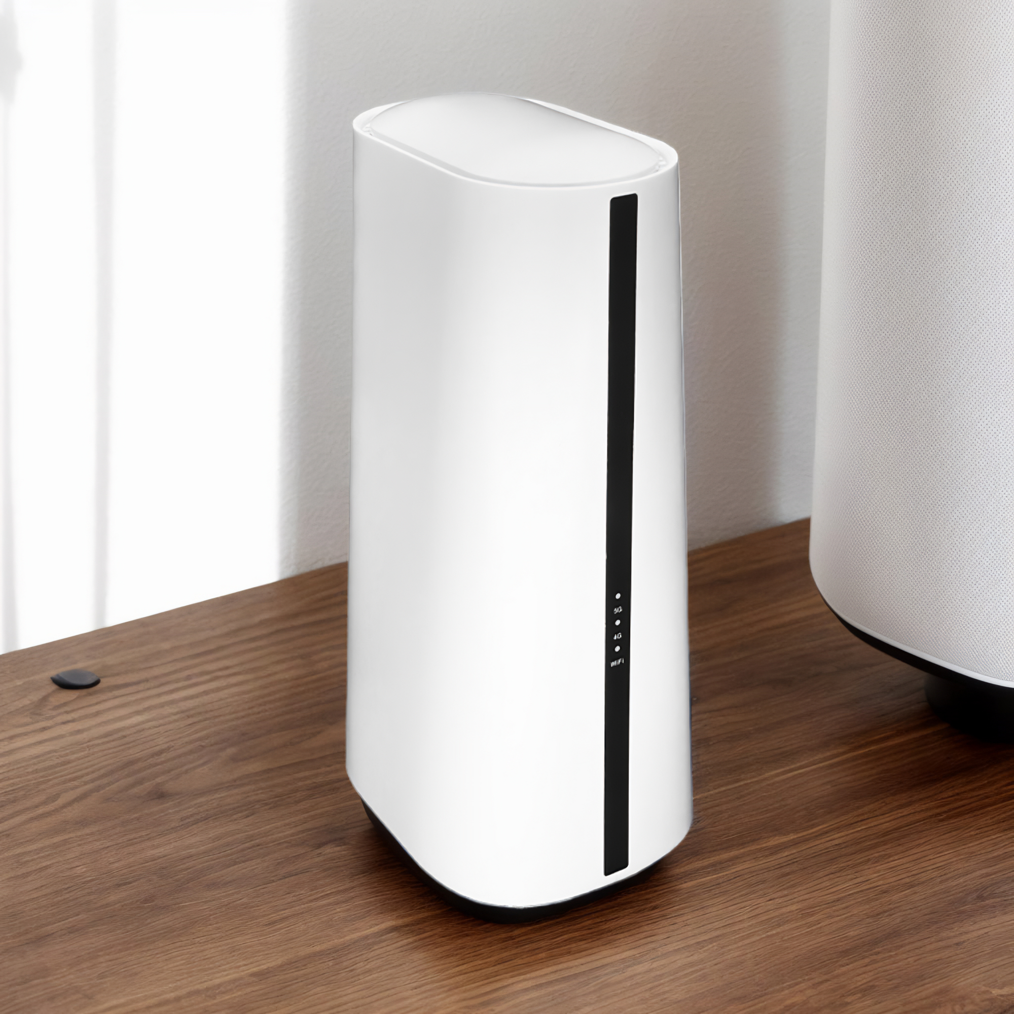 Ein weißer Router mit schwarzem Streifen auf einem Holztisch. Im Hintergrund ist ein weißer Lautsprecher teilweise sichtbar.