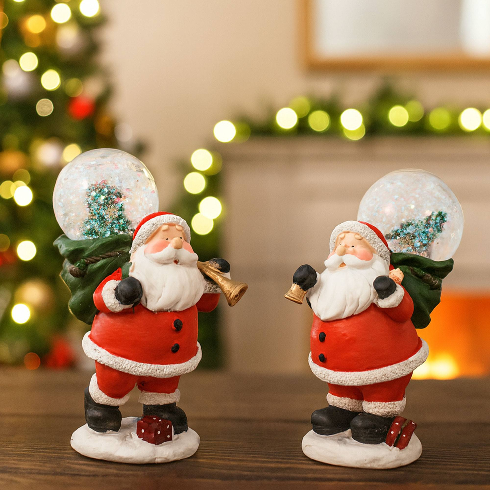 Dos figuras de Papá Noel, sosteniendo instrumentos musicales y globos de nieve. Árbol de Navidad y chimenea borrosos.