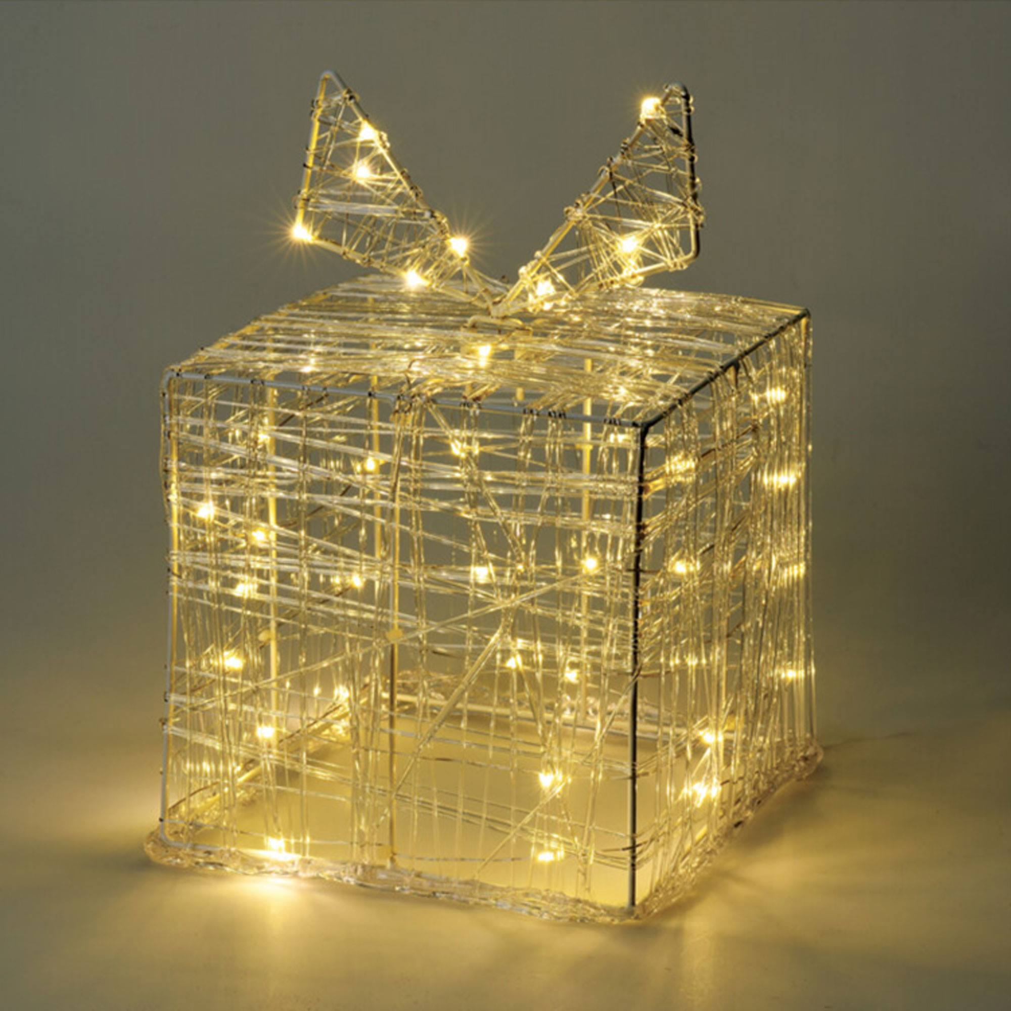 Una decoración en forma de regalo navideño iluminado. Tiene un lazo en la parte superior y está lleno de luces.