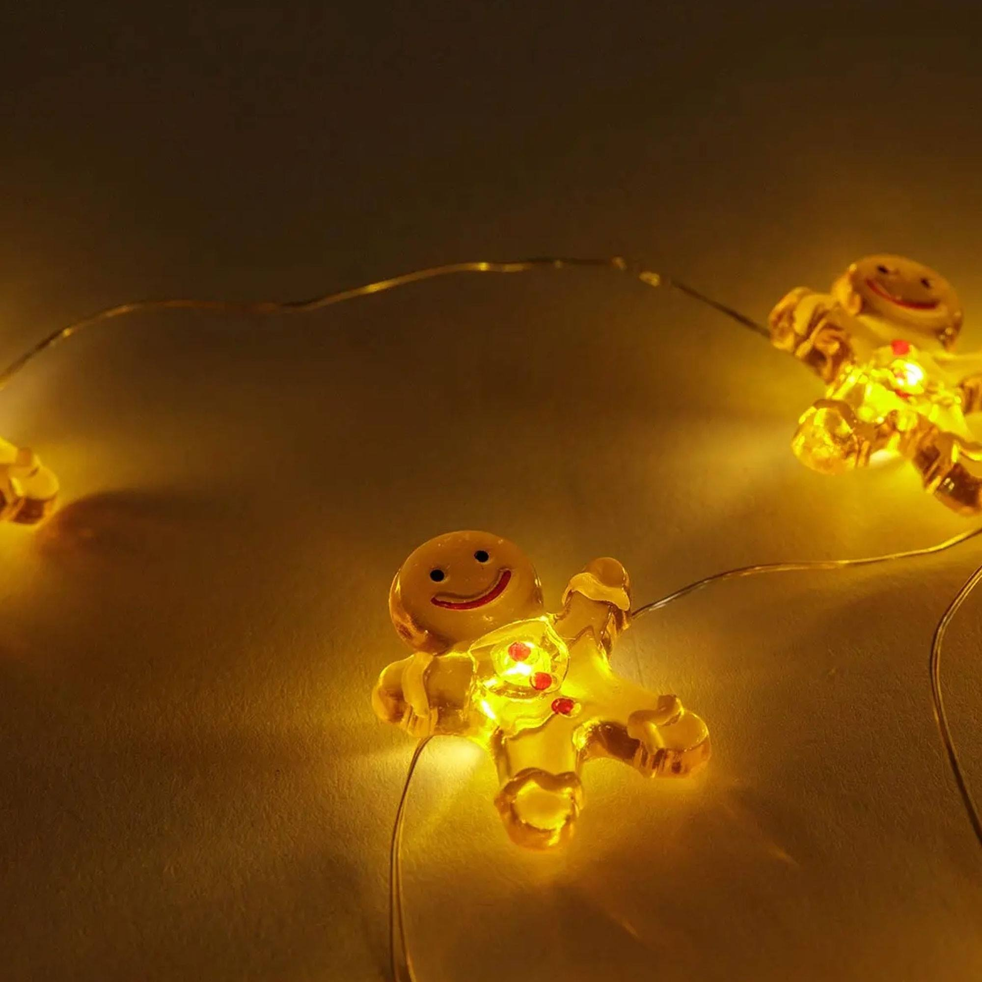 Cadena de luces de hombre de jengibre sobre fondo dorado. Cada luz tiene una cara sonriente.