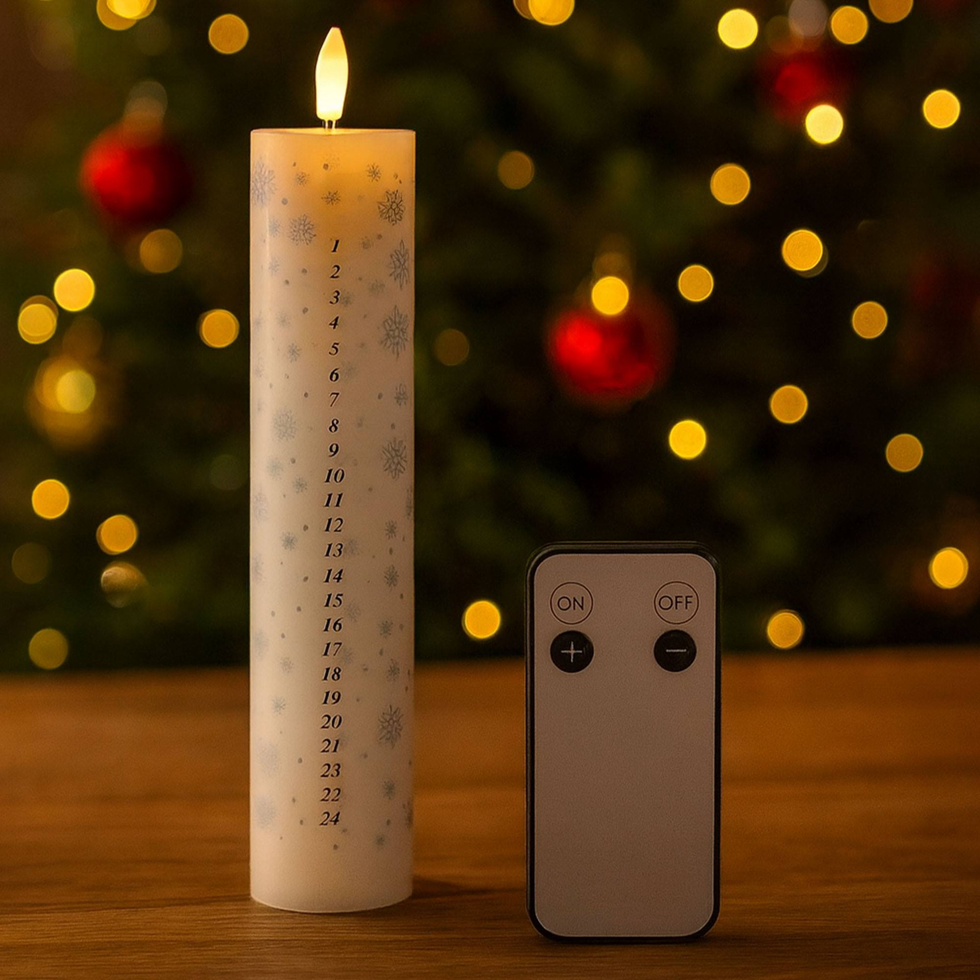 Una vela de Adviento encendida con copos de nieve y números, junto a un mando a distancia. Árbol de Navidad al fondo.