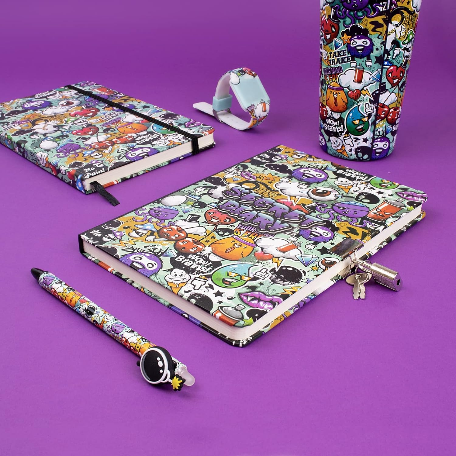 Auf einer lila Oberfläche befinden sich ein Tagebuch, ein Notizbuch, ein Stift, ein Becher und eine Uhr, alle mit bunten Graffiti-Designs.